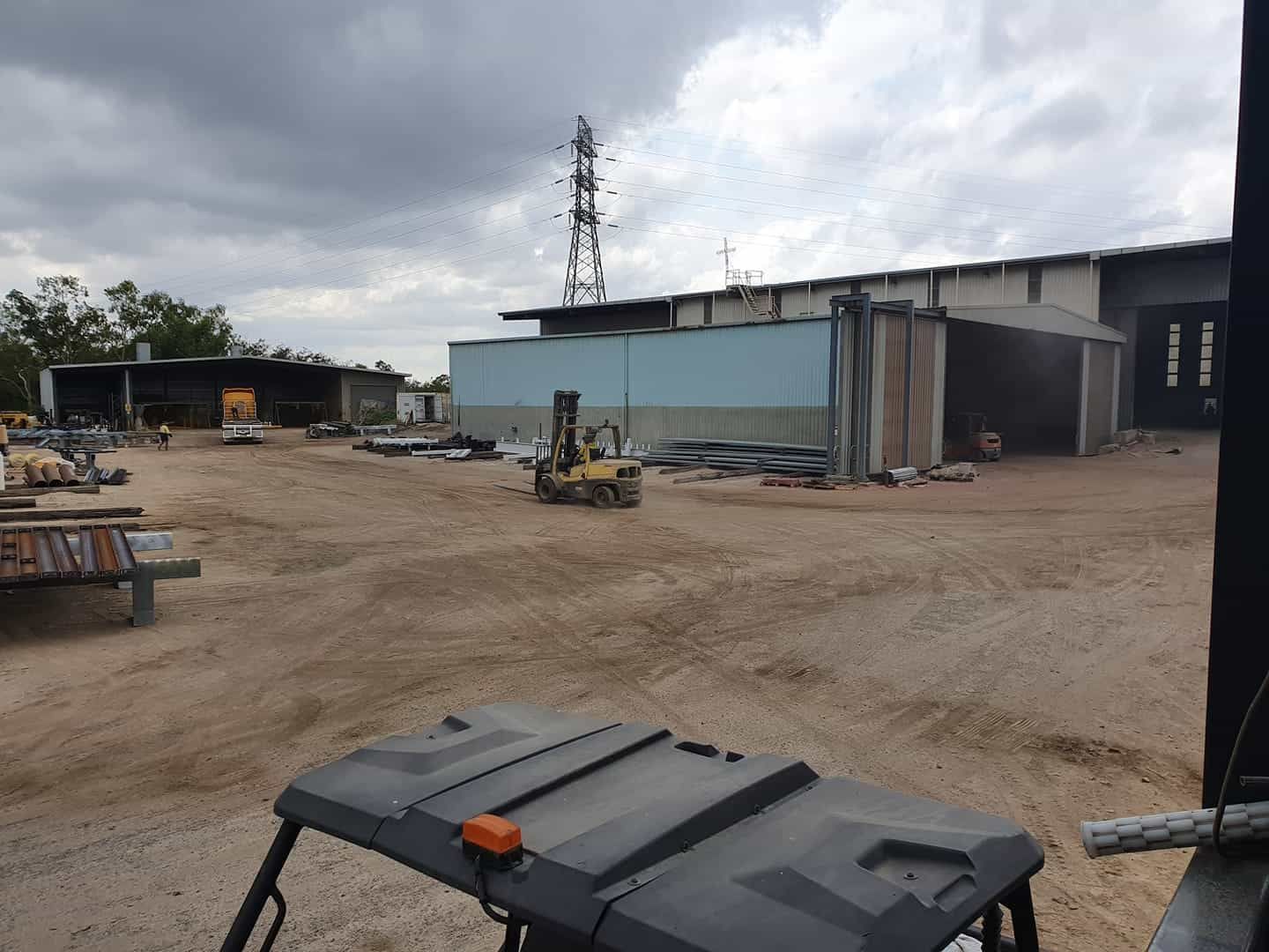 A Forklift is Parked in a Dirt Field in Front of a Building — Waters Abrasive Blasting Services In Shaw, QLD