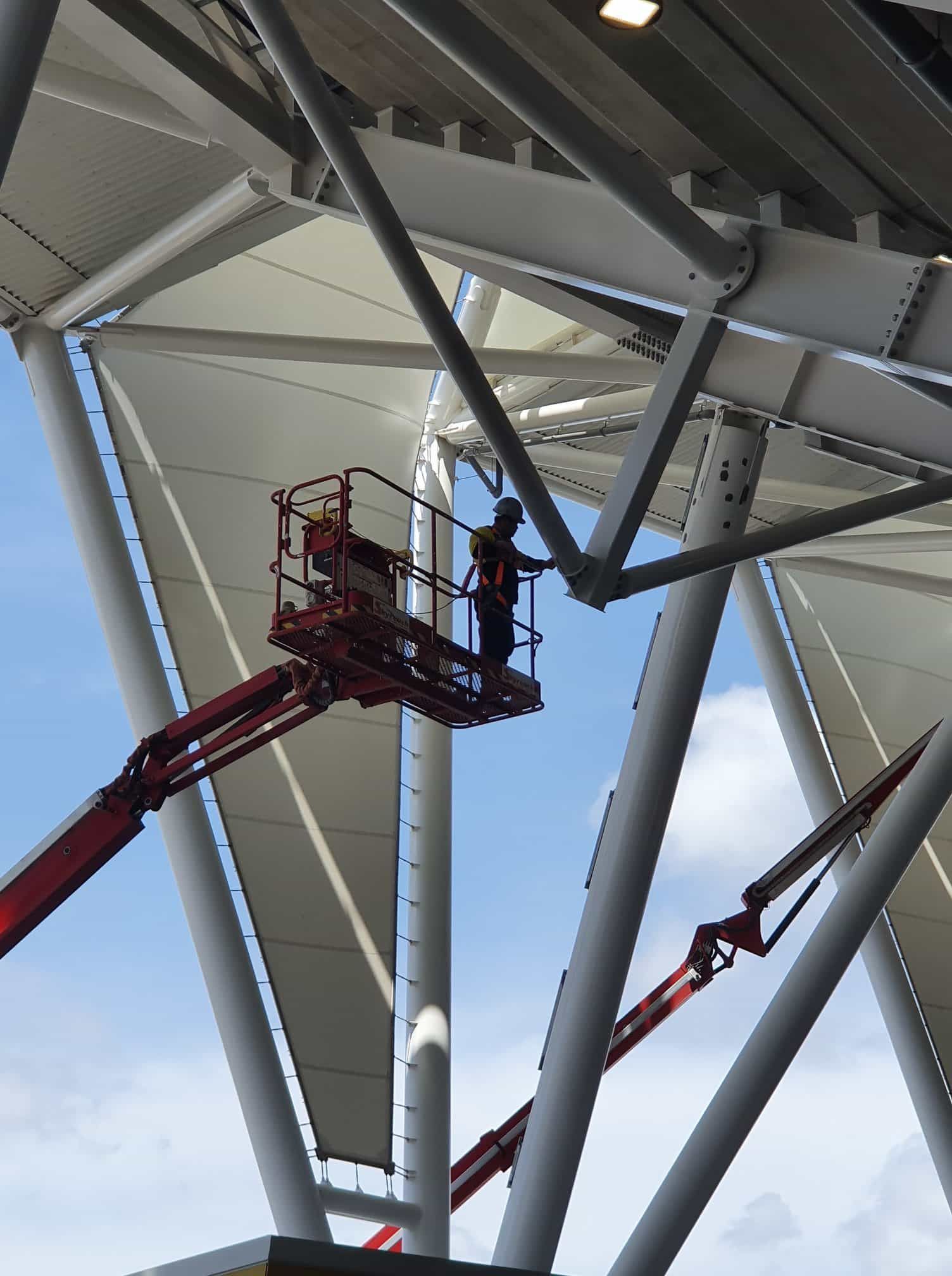A Man is Standing on a Lift Under a Roof — Waters Abrasive Blasting Services In Shaw, QLD