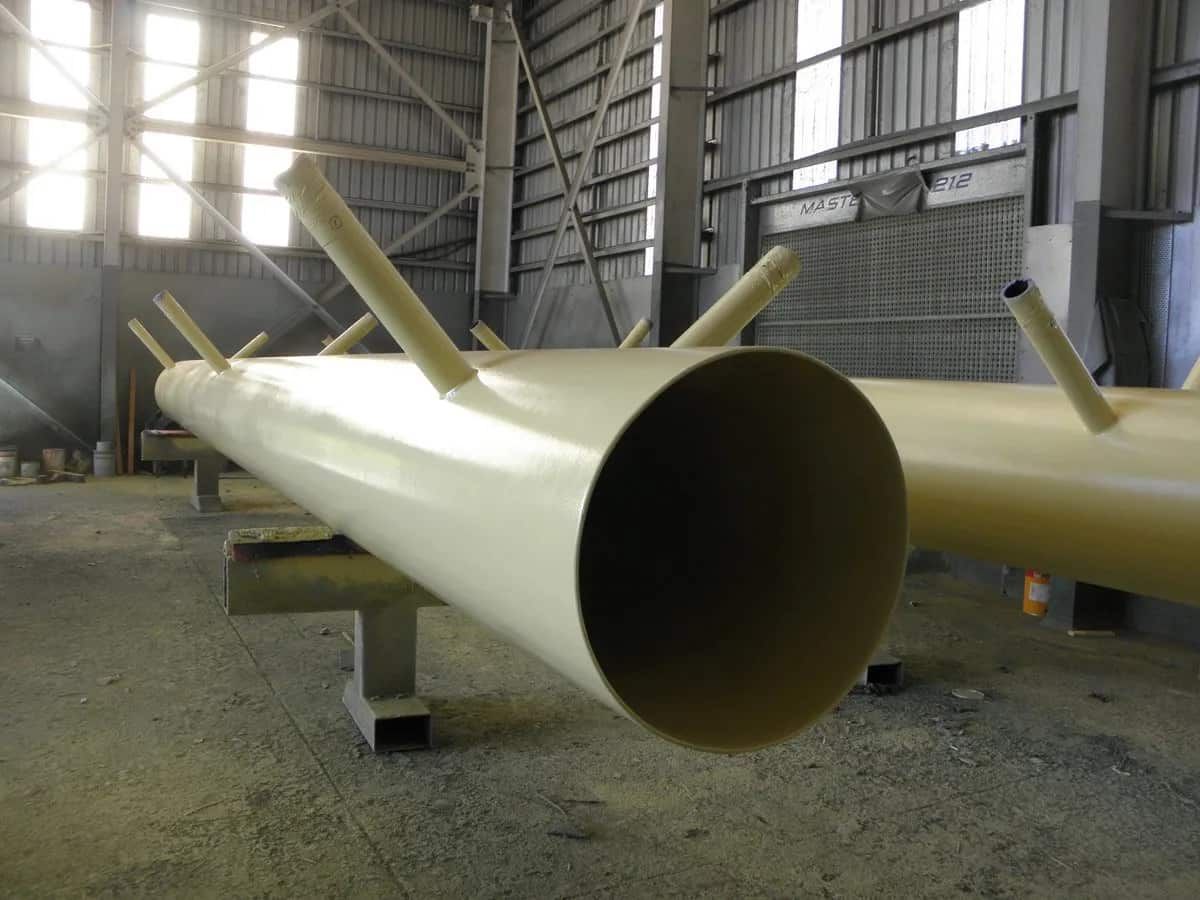 A Large Pipe is Sitting in a Warehouse With Other Pipes — Waters Abrasive Blasting Services In Shaw, QLD