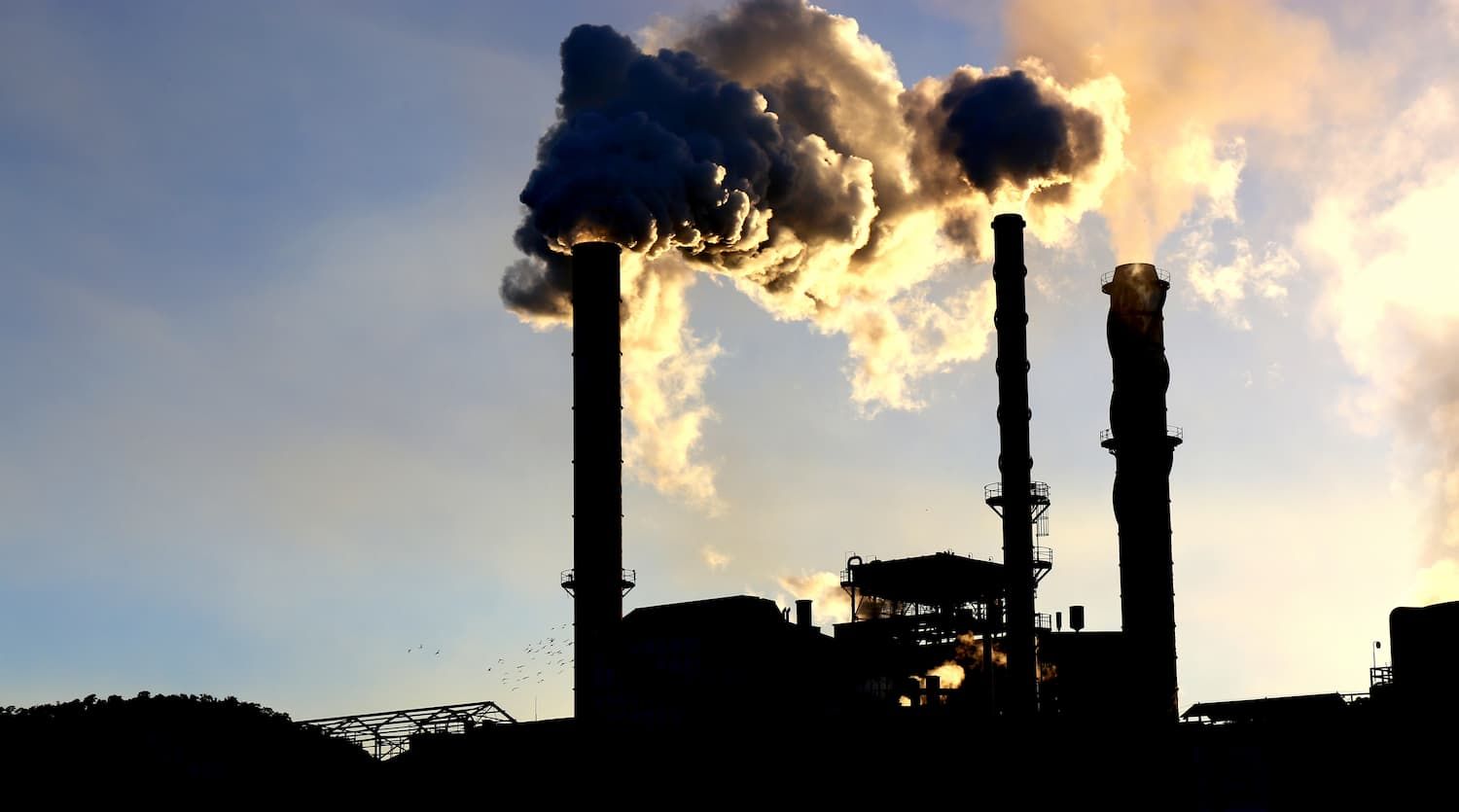 Smoke is Coming Out of the Chimneys of a Factory — Waters Abrasive Blasting Services In Shaw, QLD