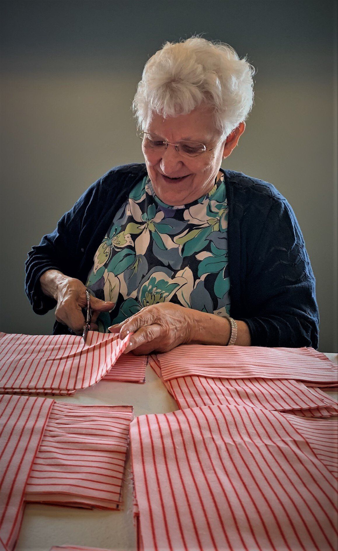 Elderly Woman Happily Cutting Striped Fabric