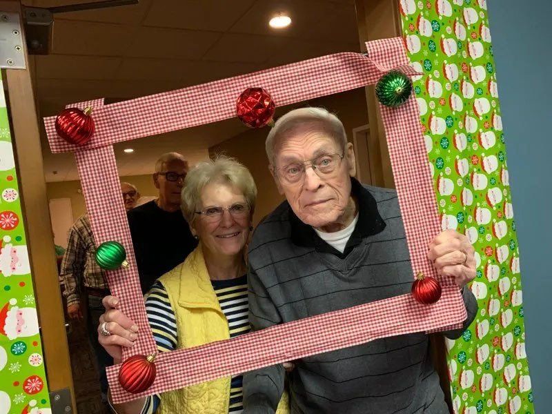 Happy Seniors Posing with Handheld Christmas Ornament Frame