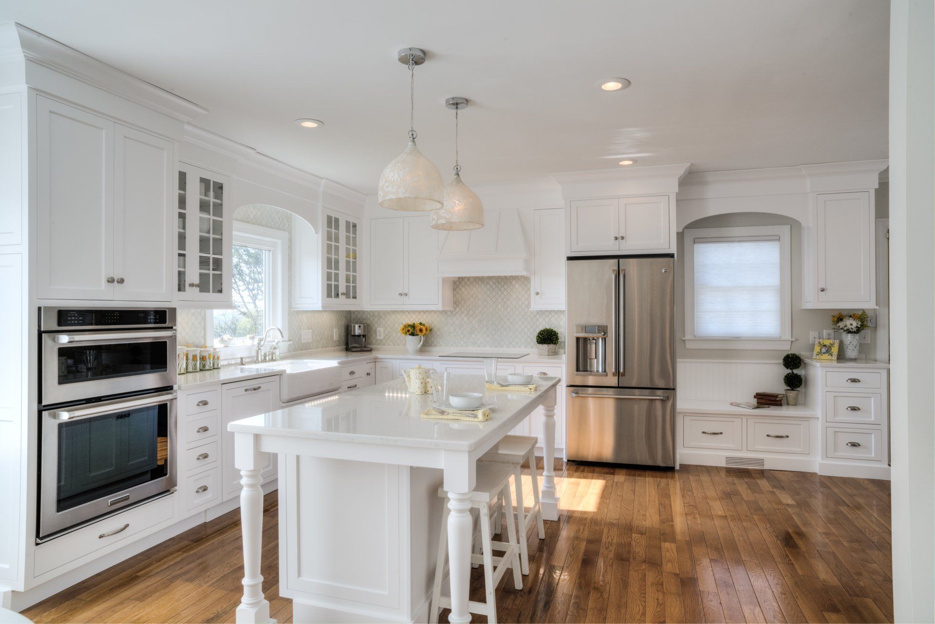 White kitchen with island, stainless steel appliances, and wooden floor.