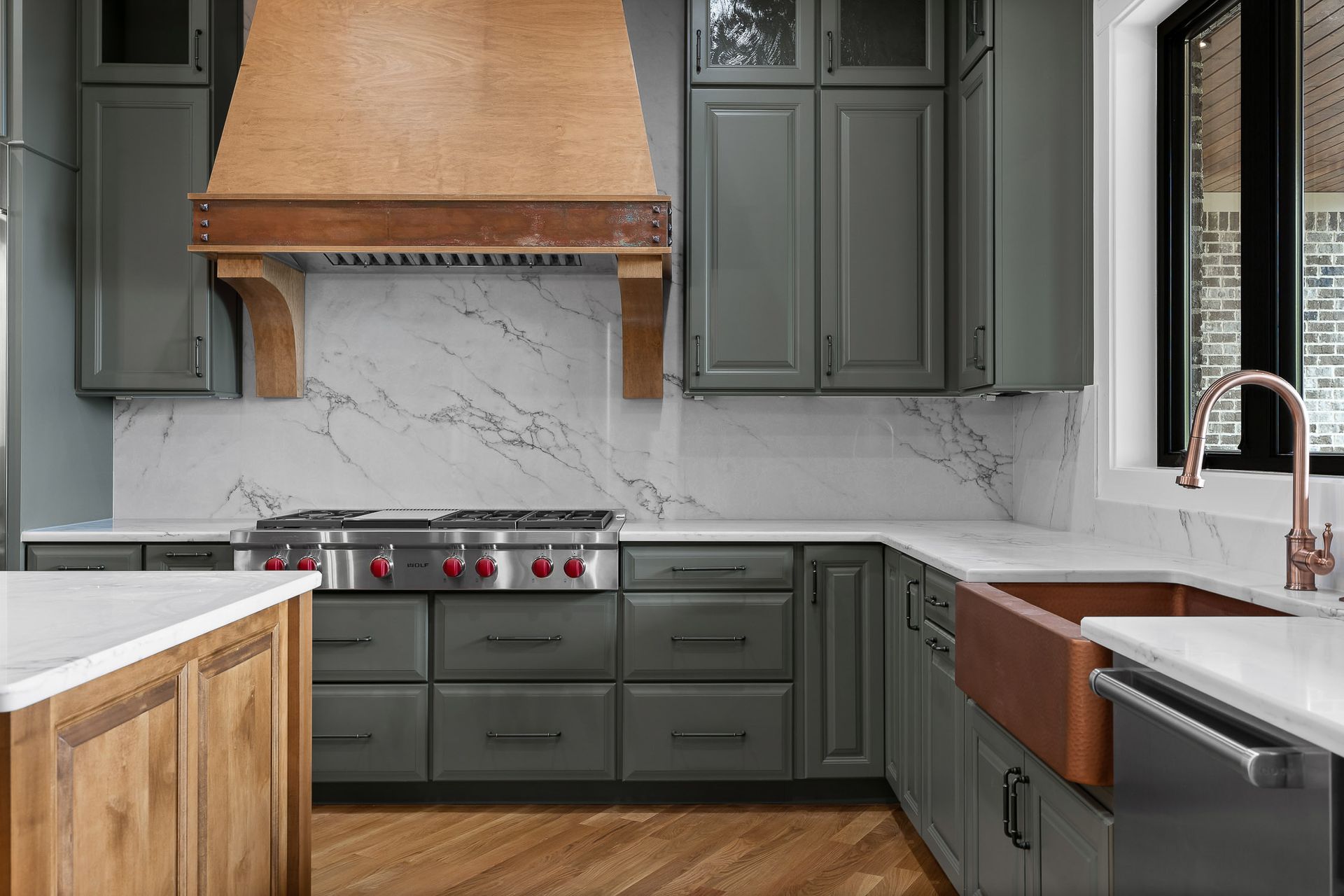 Gray kitchen with a wood hood, copper sink, and white marble backsplash.