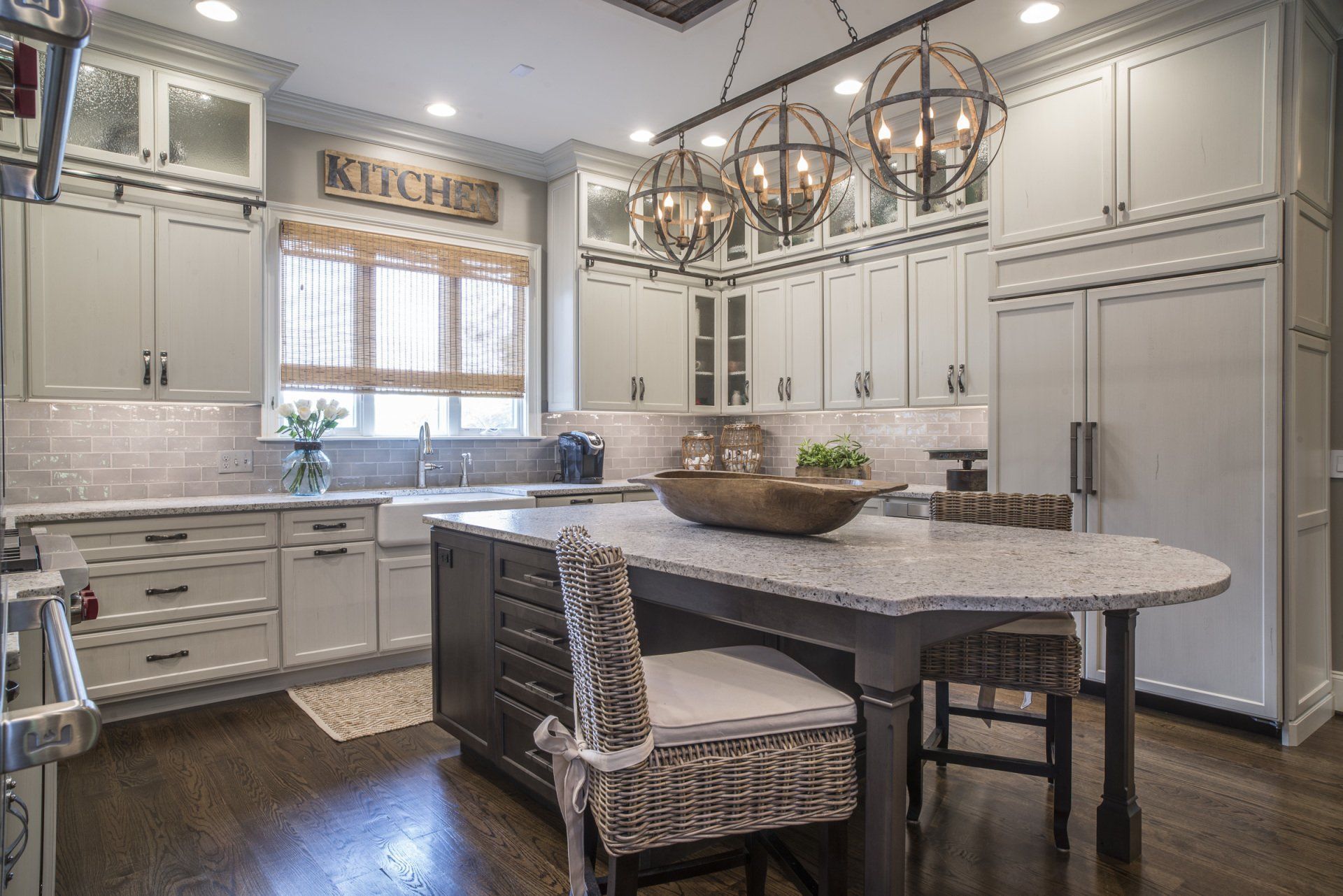 Elegant kitchen with light gray cabinets, a dark island, and a globe chandelier.