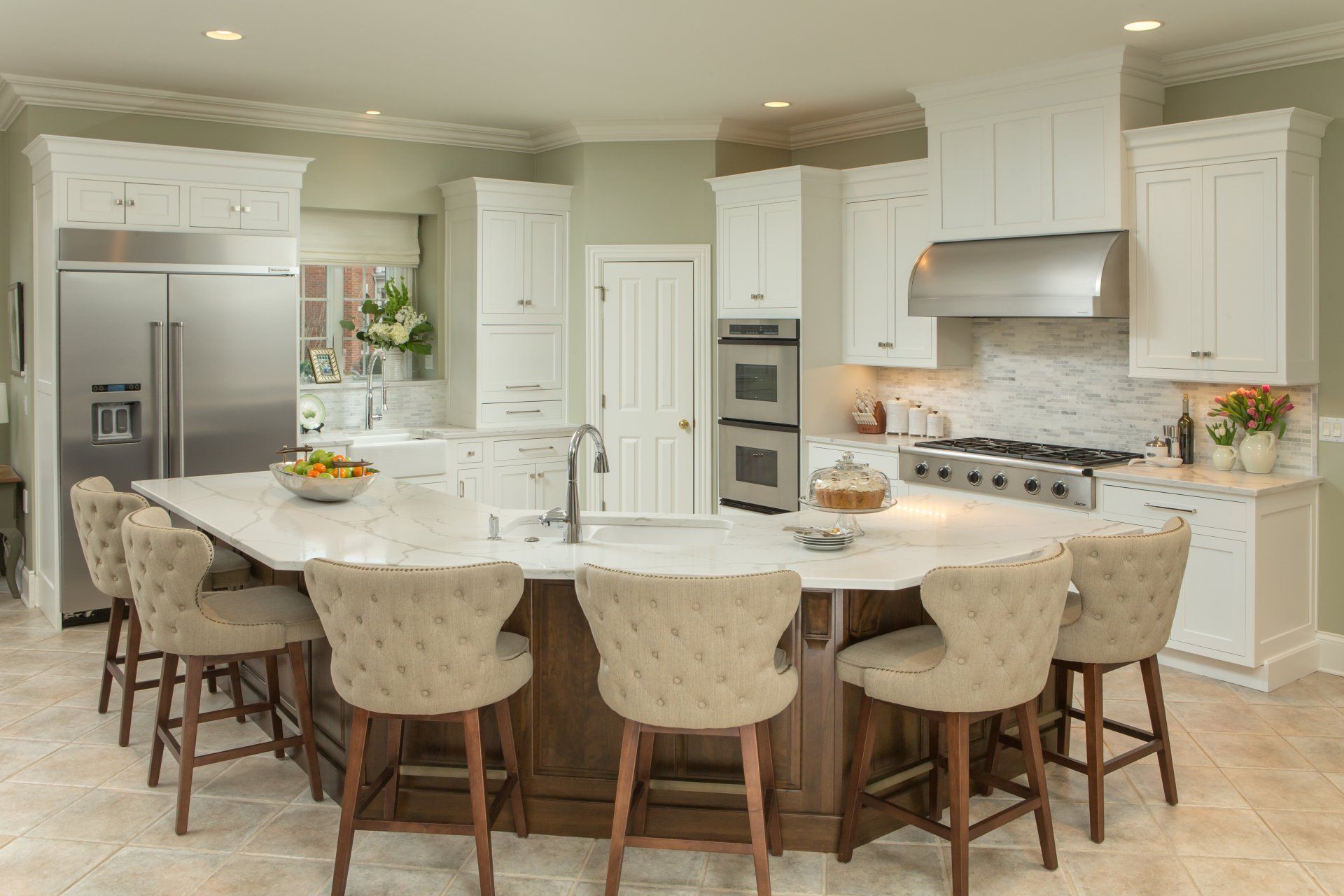 Elegant kitchen with a large island, seating, stainless steel appliances, and white cabinets.