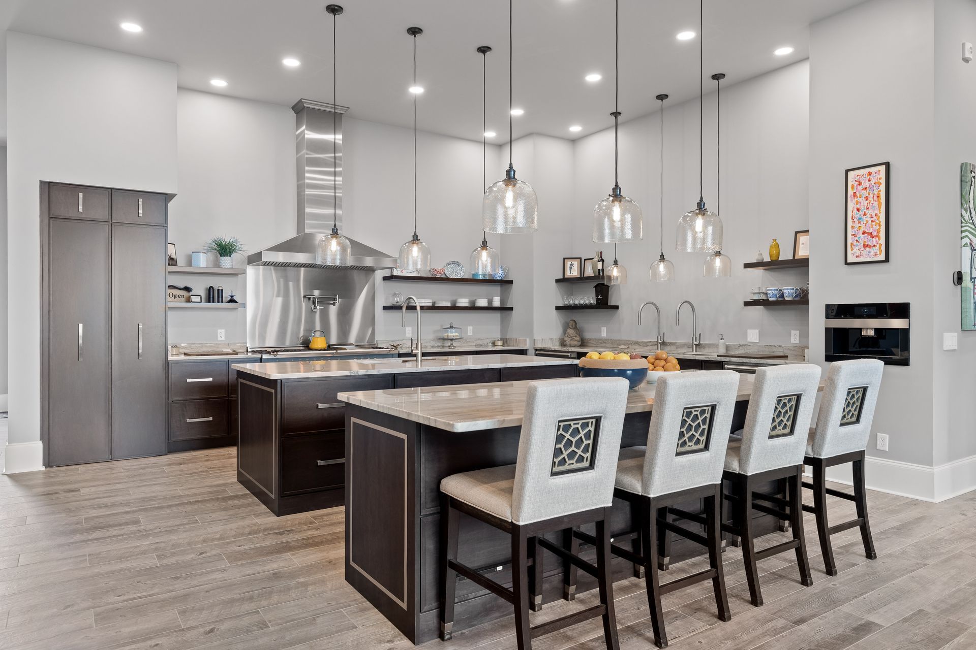Spacious modern kitchen with island seating, stainless steel appliances, and pendant lights; grey walls.