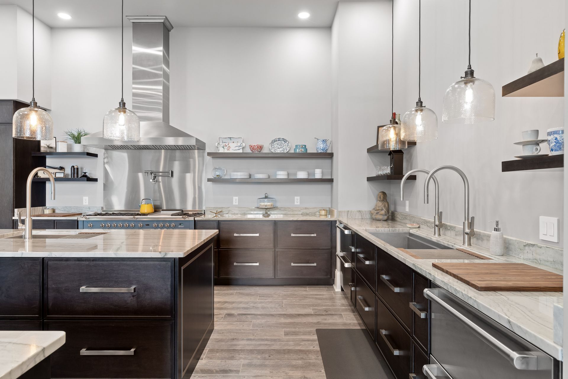 Modern kitchen with dark cabinets, stainless steel appliances, and pendant lights.