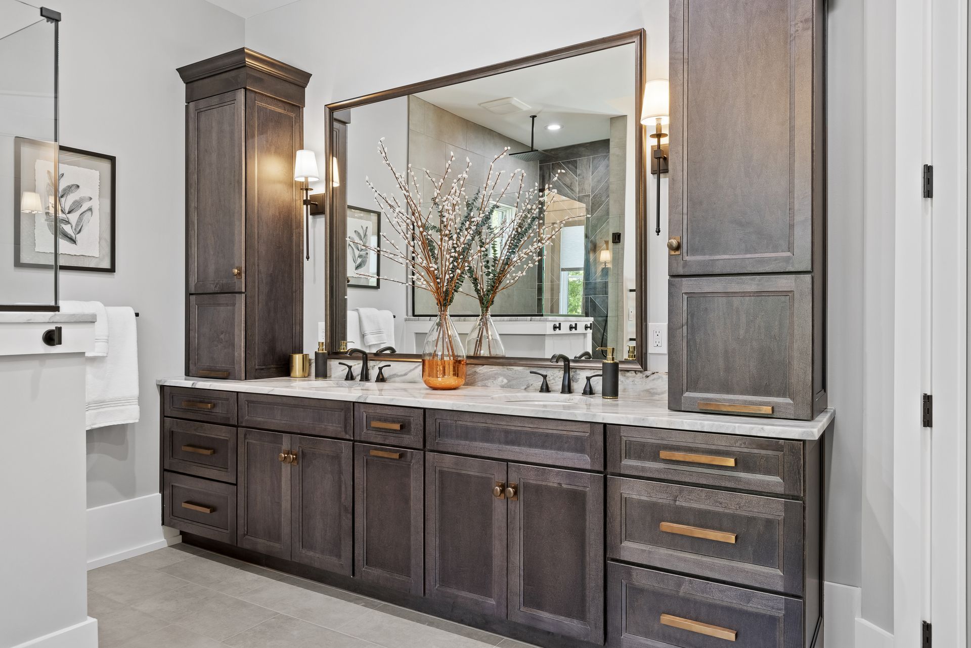 Bathroom with dark wood vanity, large mirror, and storage cabinets; neutral colors.