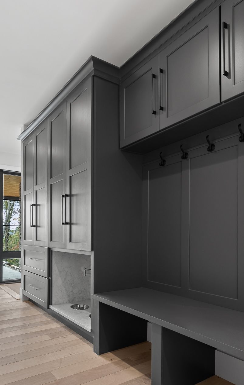 Gray built-in cabinets with a bench, hooks, and overhead storage in a mudroom.