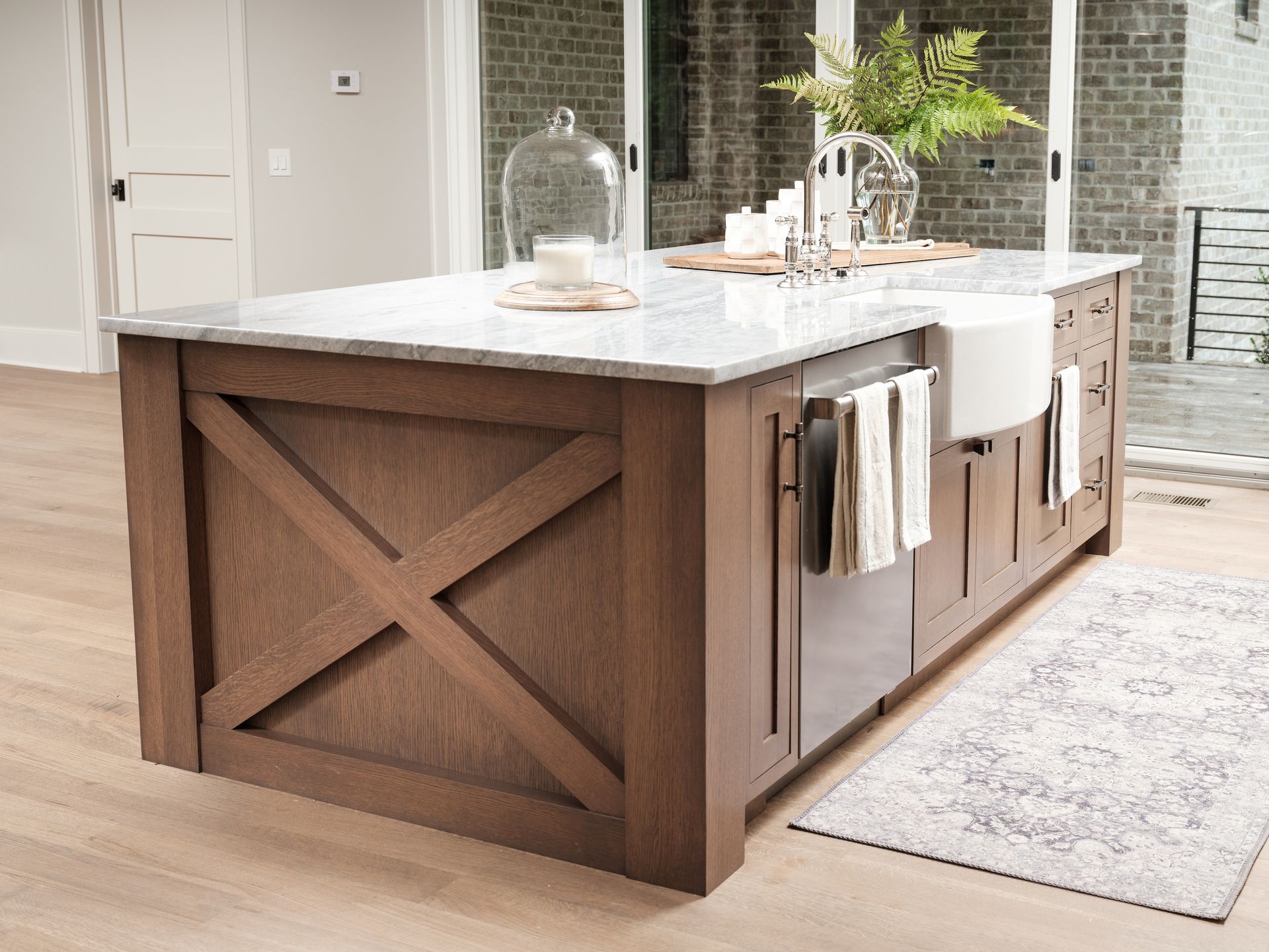 Kitchen island with wood X detailing, white countertop, and farmhouse sink.
