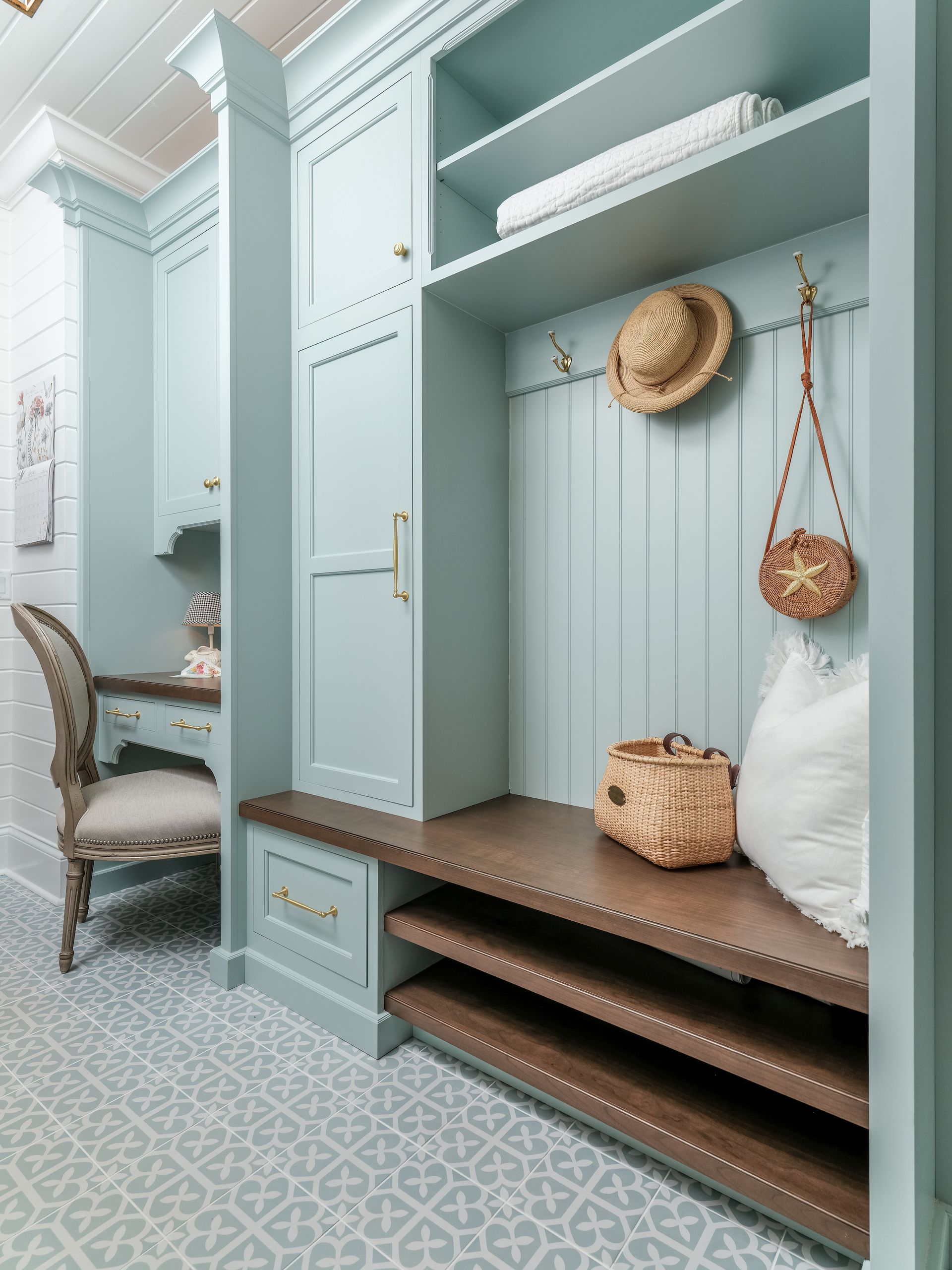 Light blue entryway with bench, shelves, hat, and a desk.