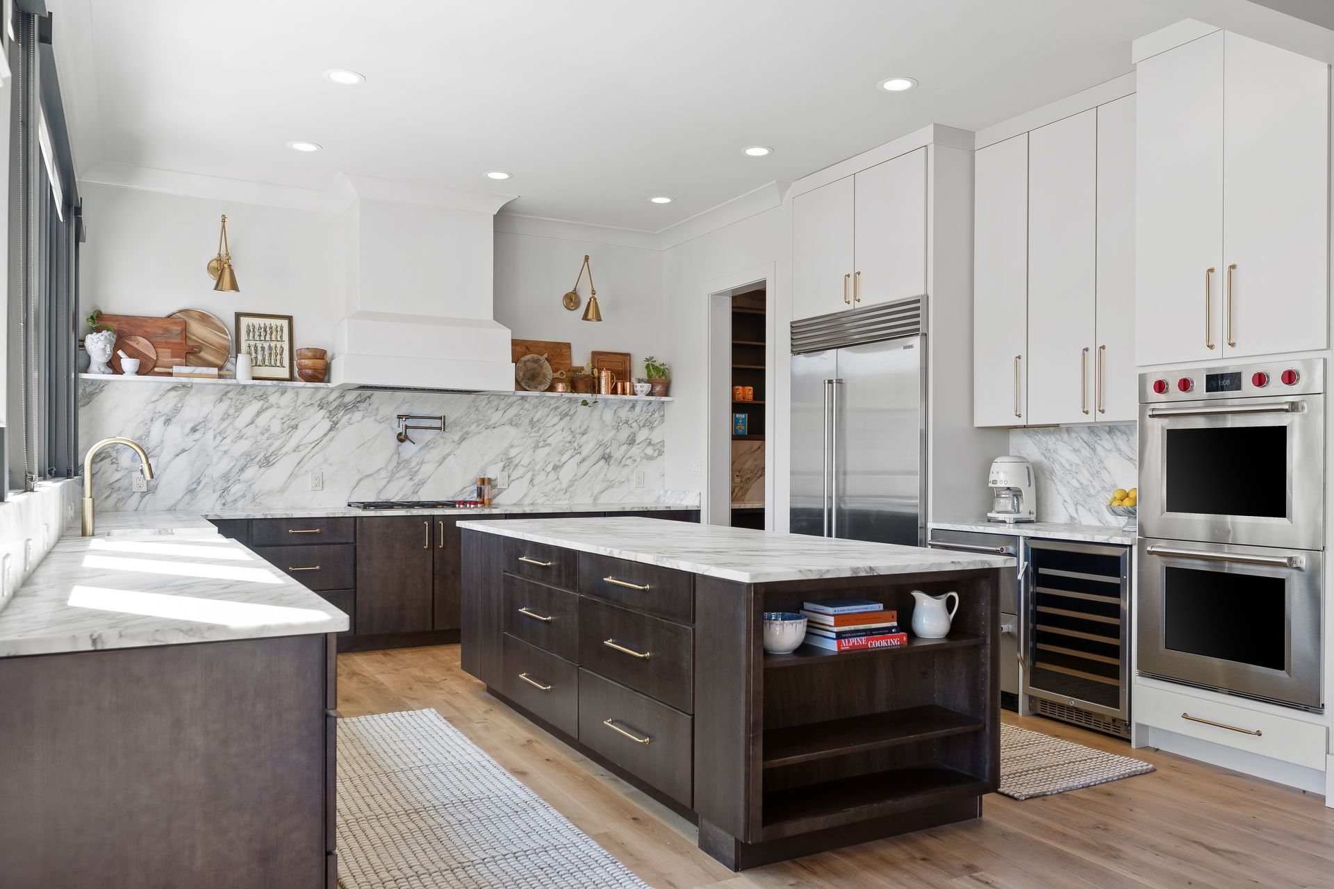 Modern kitchen with white and dark brown cabinets, marble countertops, and a large island.