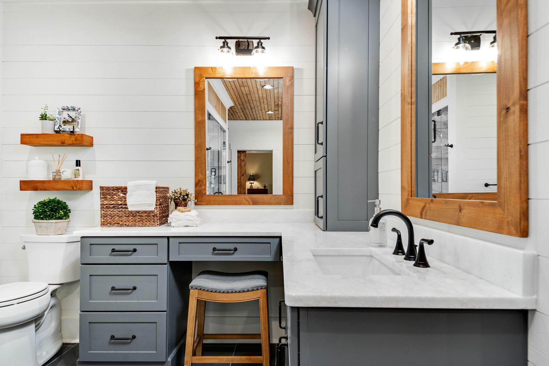 Bathroom with gray vanity, wood-framed mirrors, white countertop, and shiplap walls.