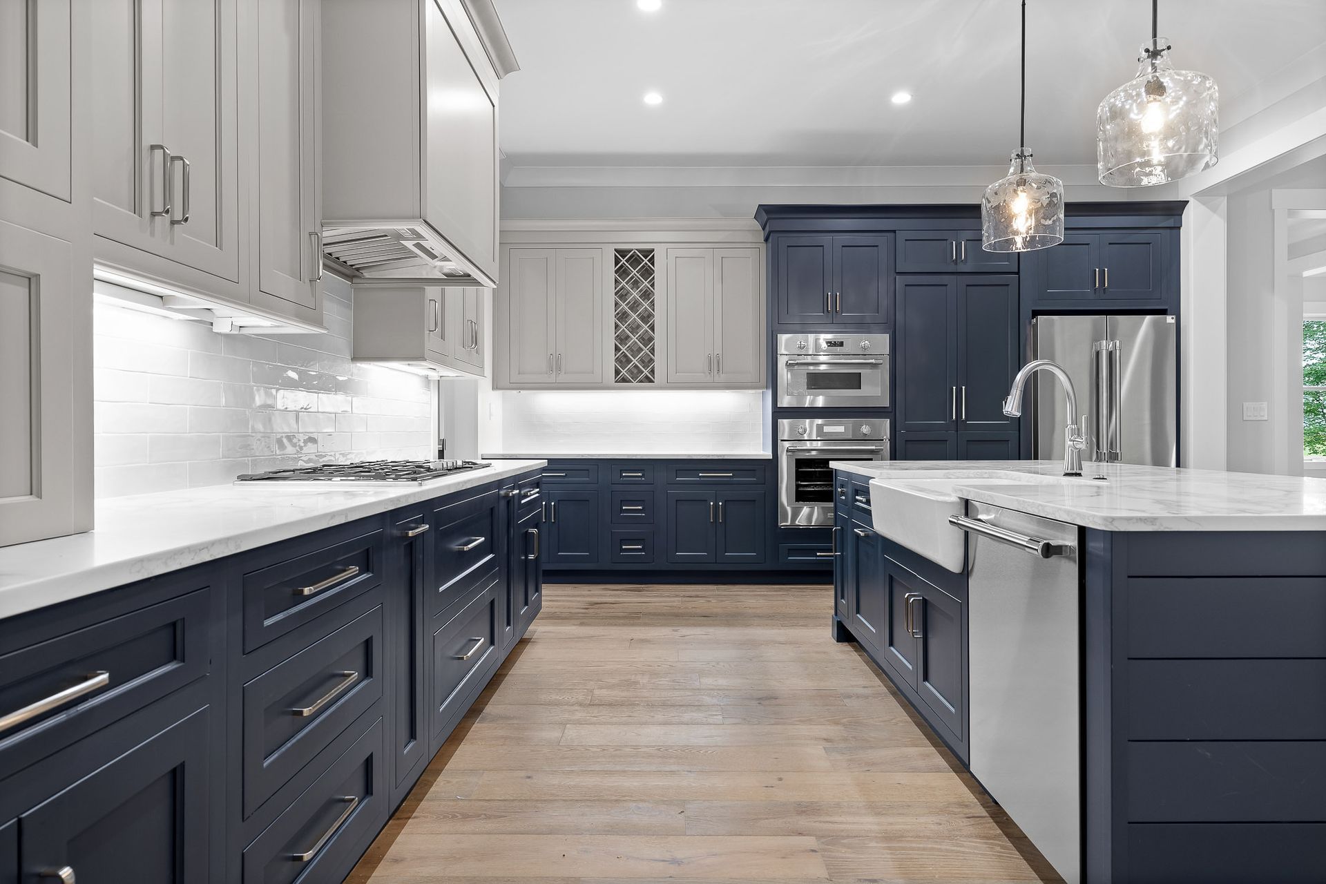 Modern kitchen with blue and white cabinets, island, and stainless steel appliances.