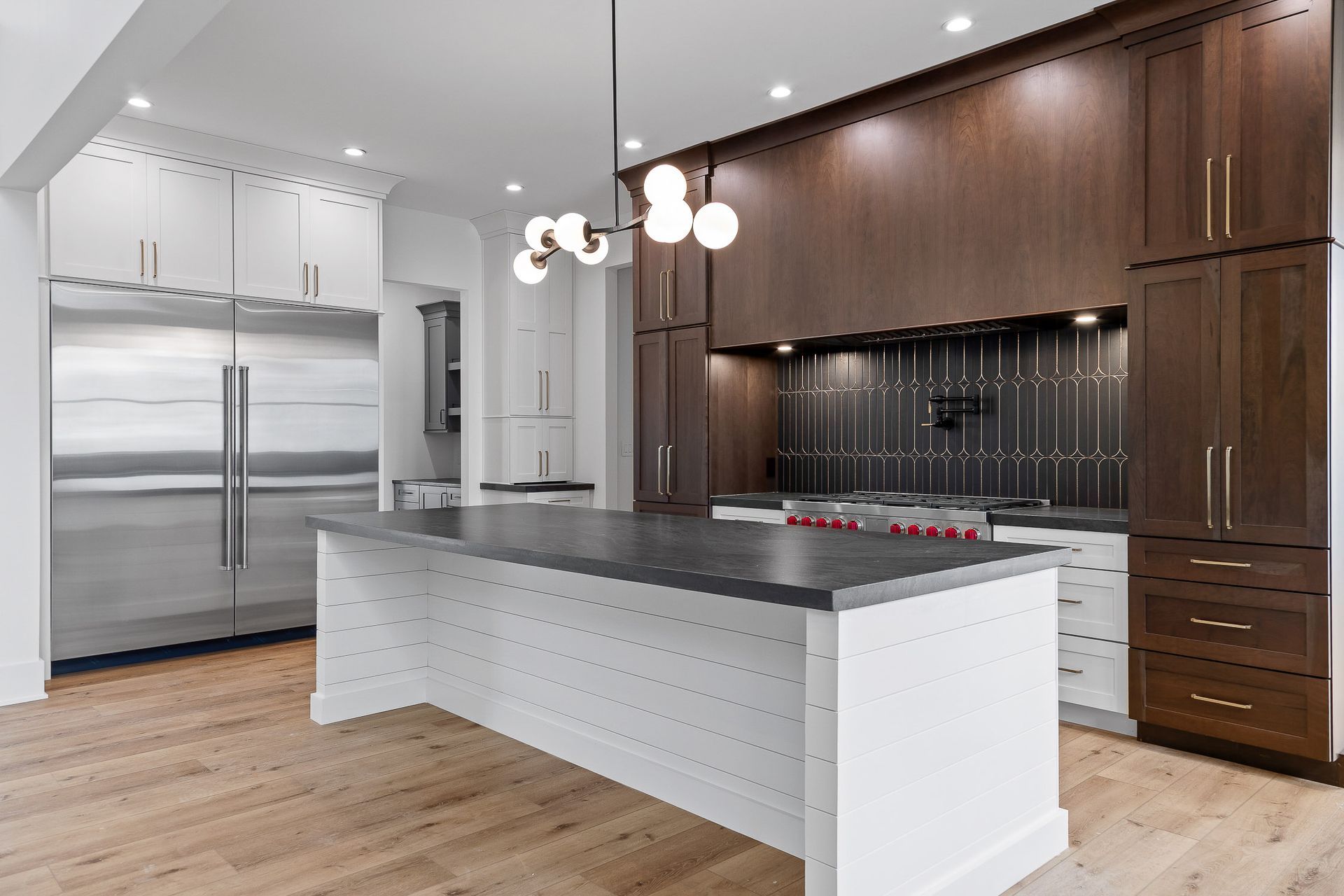 Modern kitchen with white island, stainless steel refrigerator, and dark wood cabinets.