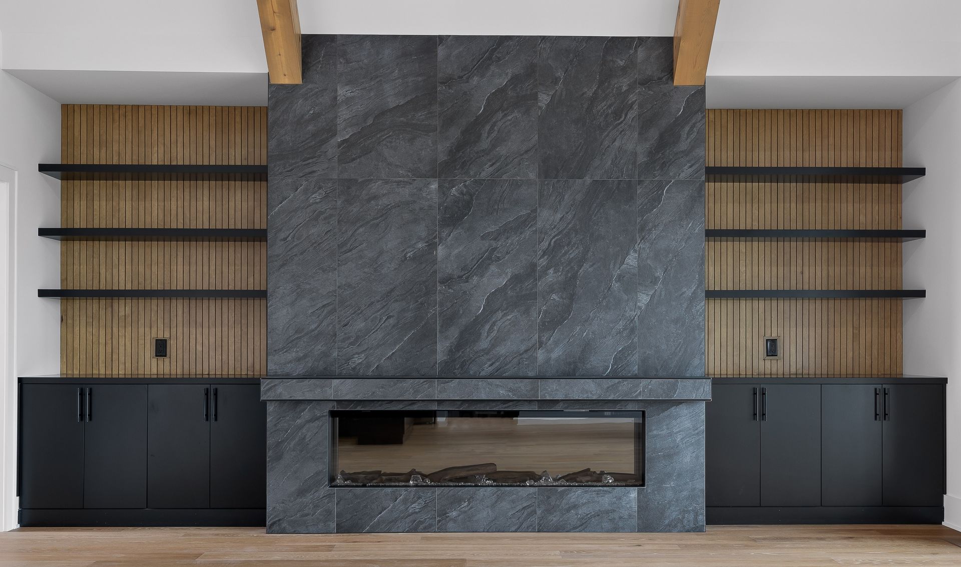 Fireplace with black stone surround, shelving, and black cabinetry.