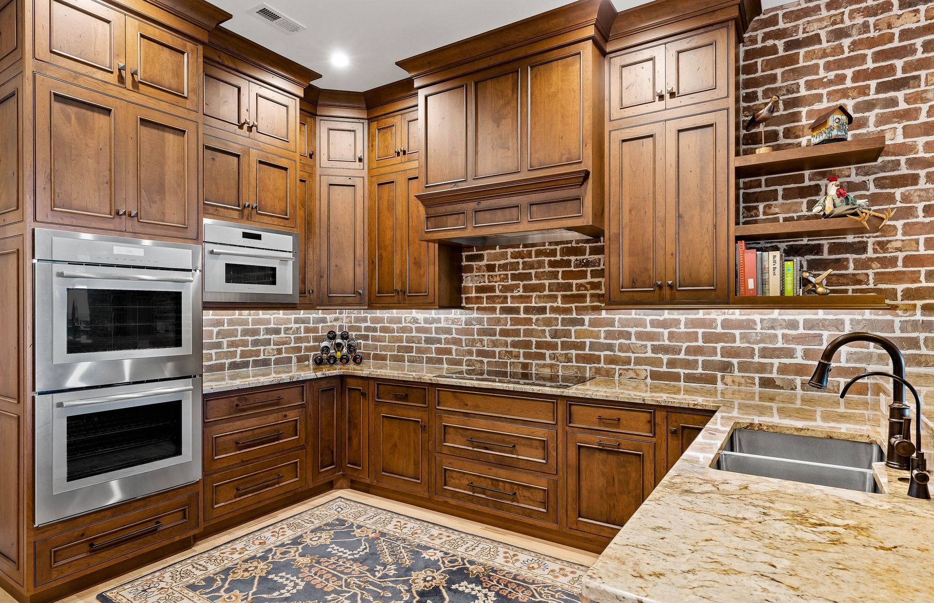 Brown kitchen with brick backsplash, stainless steel appliances, wooden cabinets, and granite countertops.