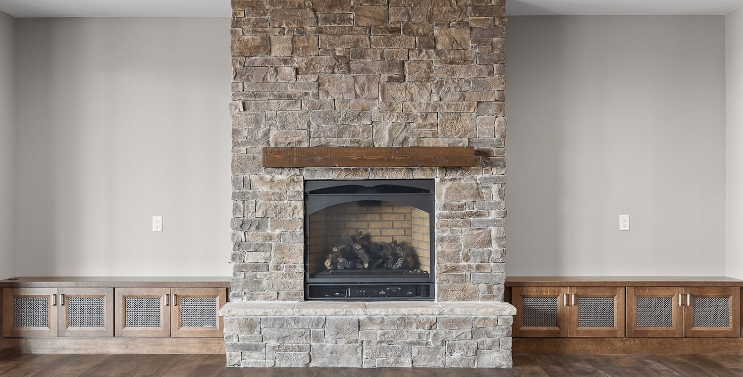 Stone fireplace with a wooden mantle and built-in cabinets.