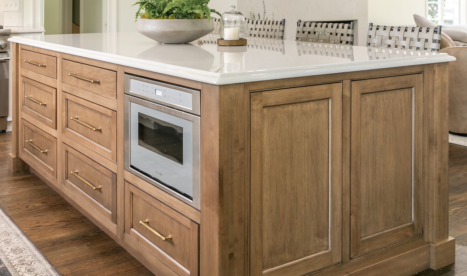 Wooden kitchen island with drawers, cabinets, a built-in microwave, and a white countertop.