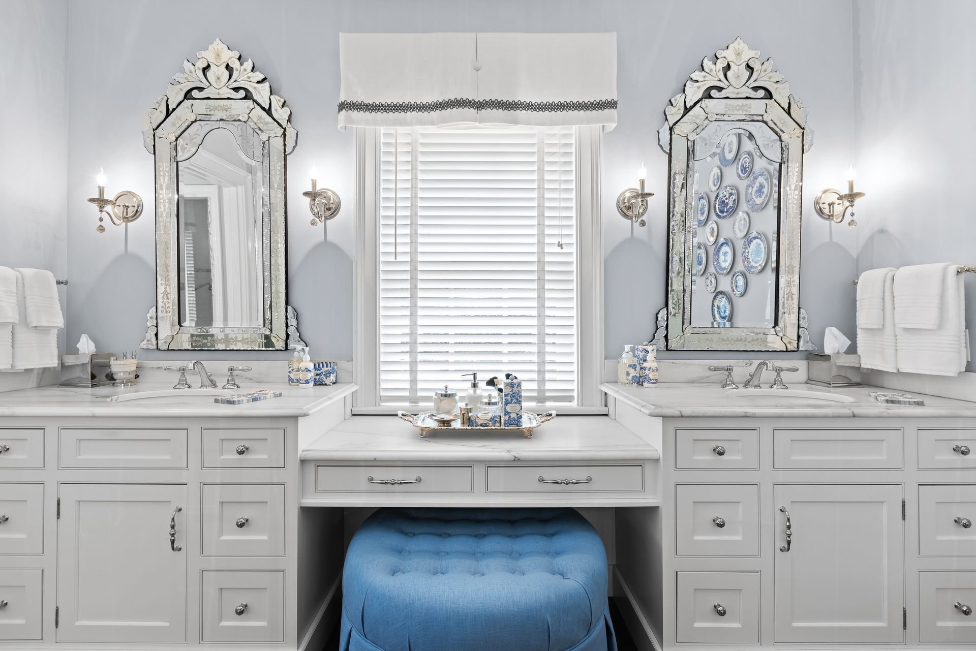 Blue and white bathroom with vanity, mirrors, and a stool.