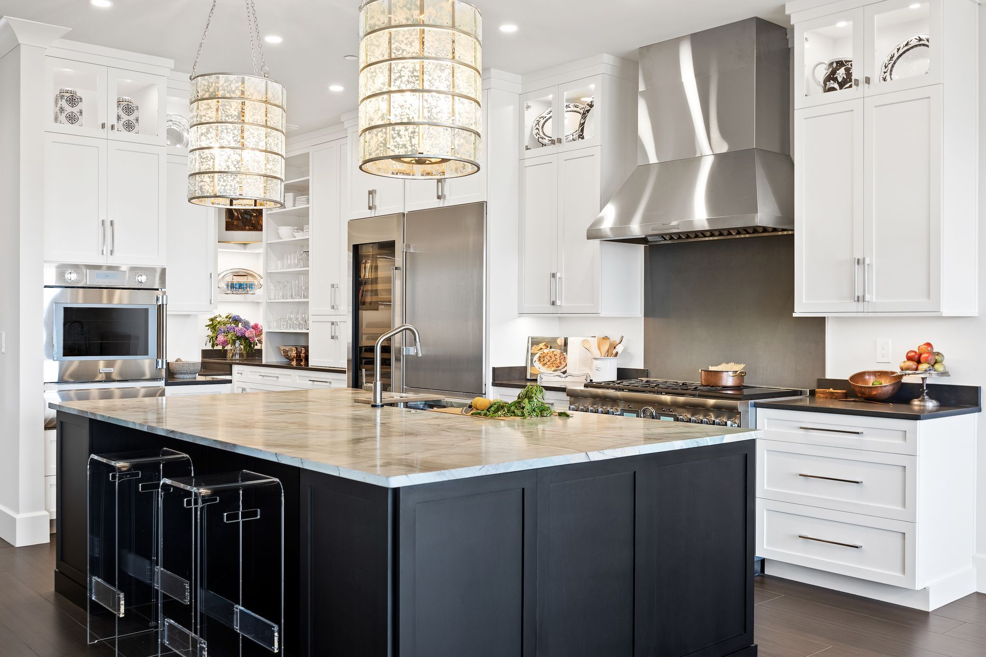 Modern kitchen with black island, white cabinets, stainless steel appliances, and pendant lights.