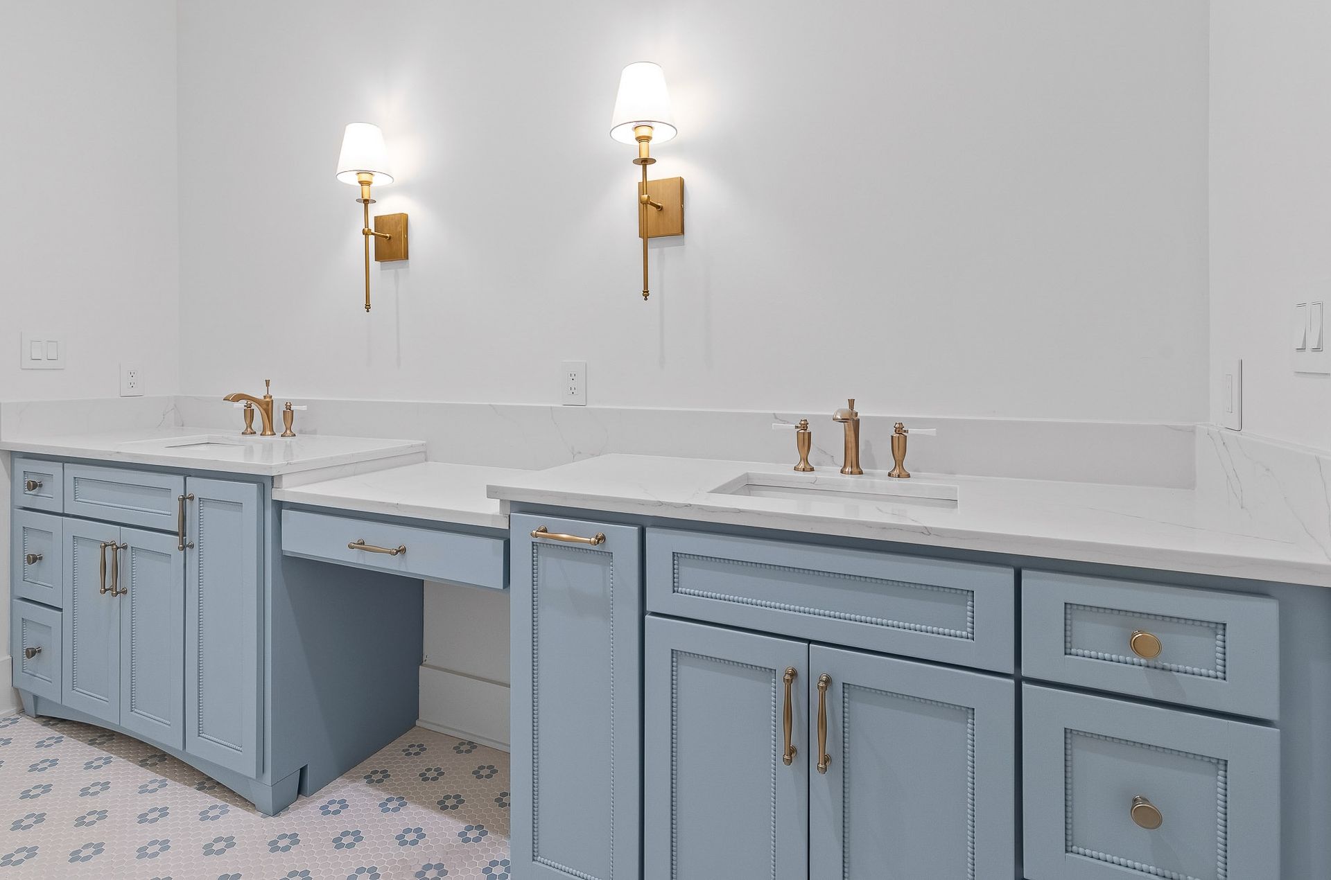Blue bathroom vanity with gold fixtures, white countertop, and sconces.