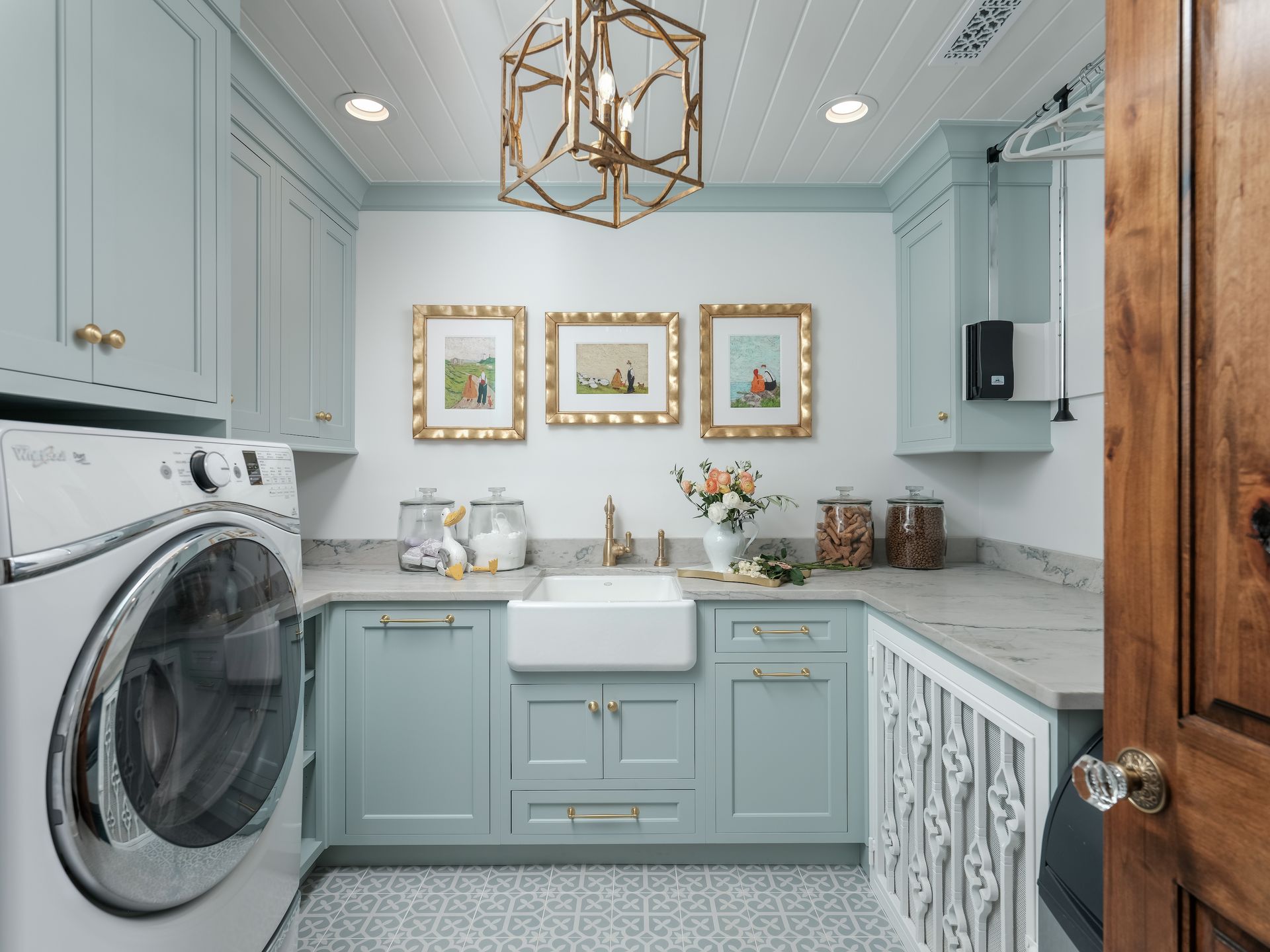 Laundry room with blue cabinets, white sink, gold accents, and washer.