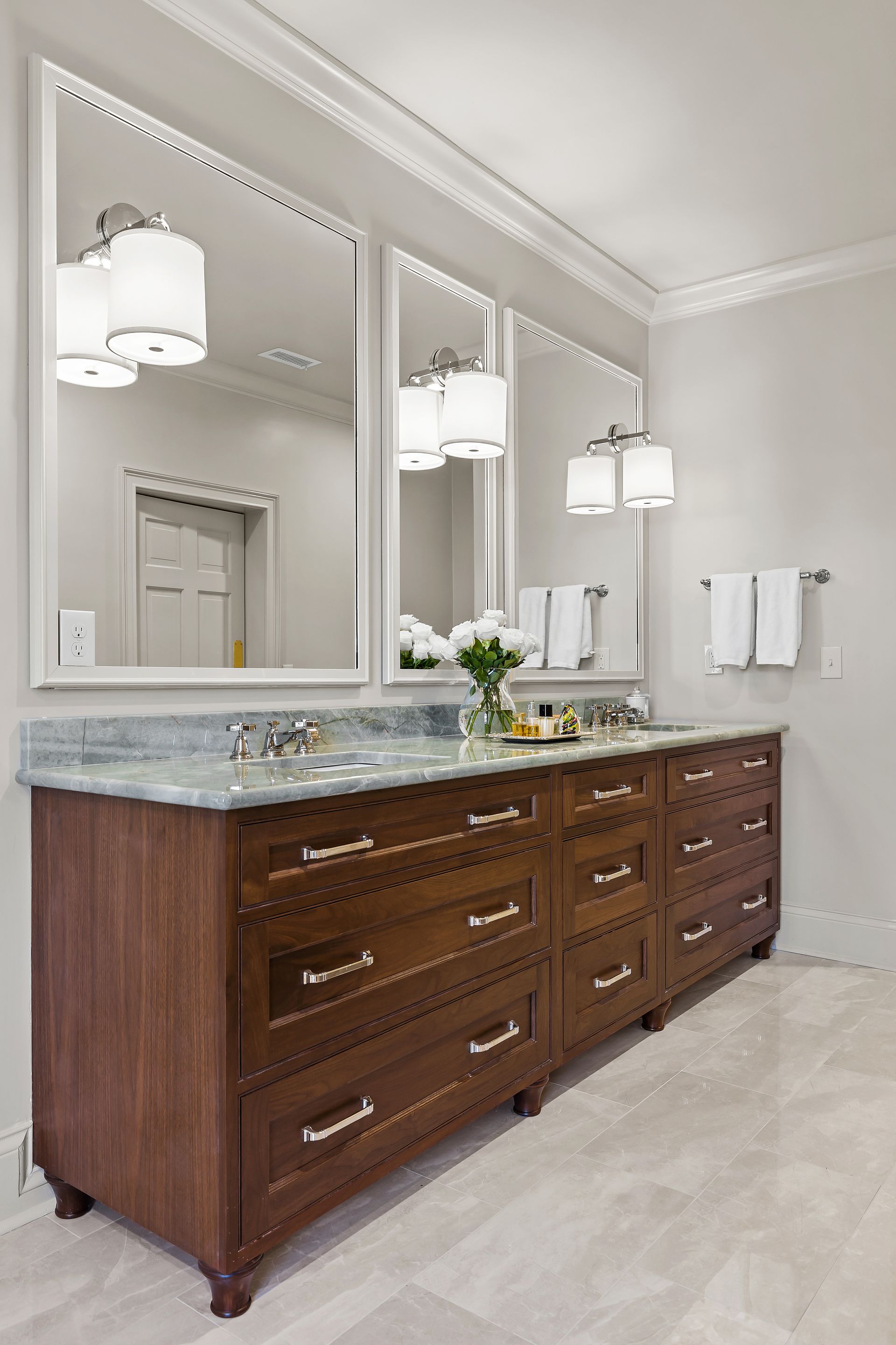 Bathroom with dark wood vanity, marble countertop, three mirrors, and white walls.