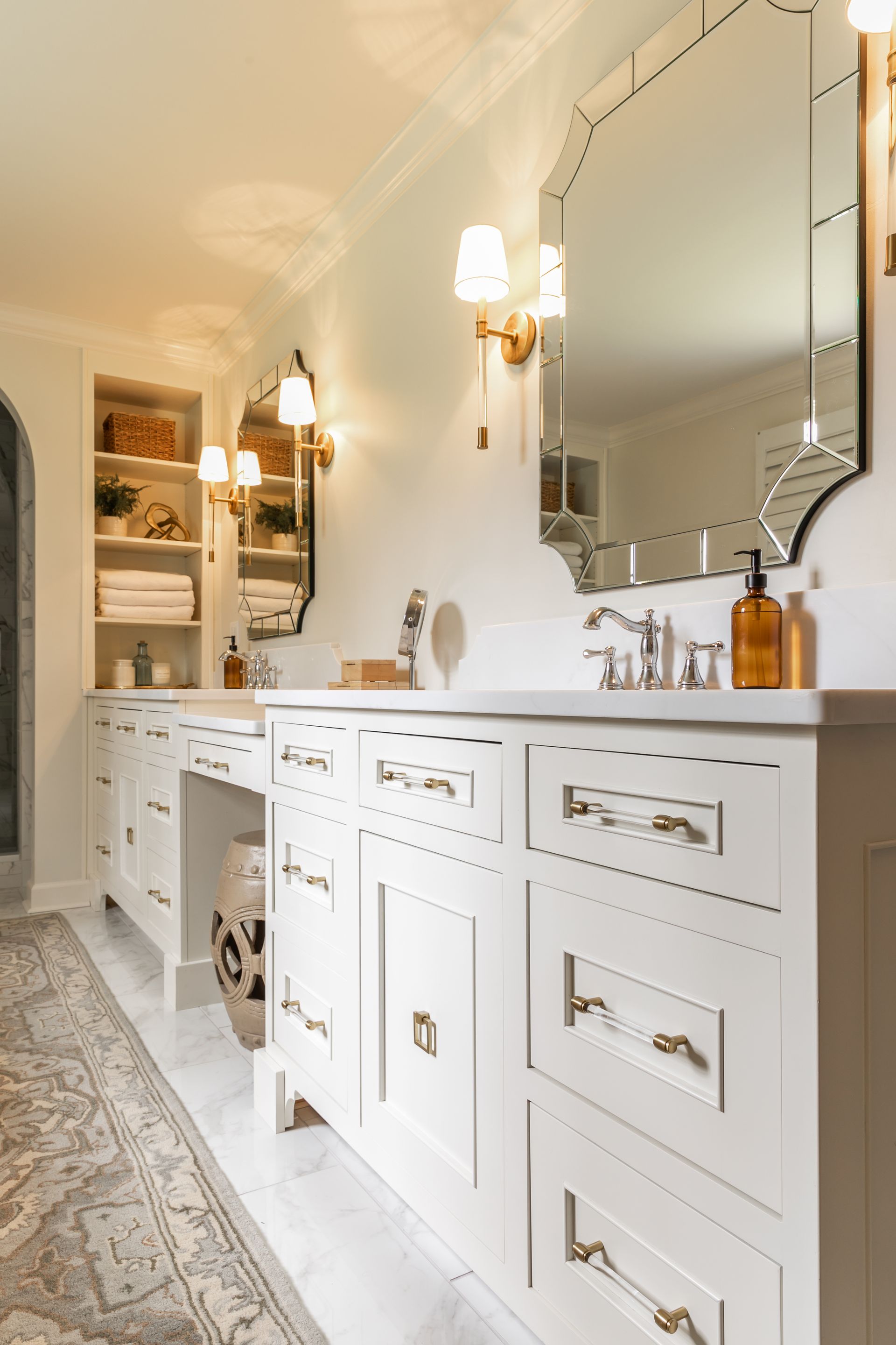Elegant white bathroom with dual sinks, ornate mirrors, and gold accents.