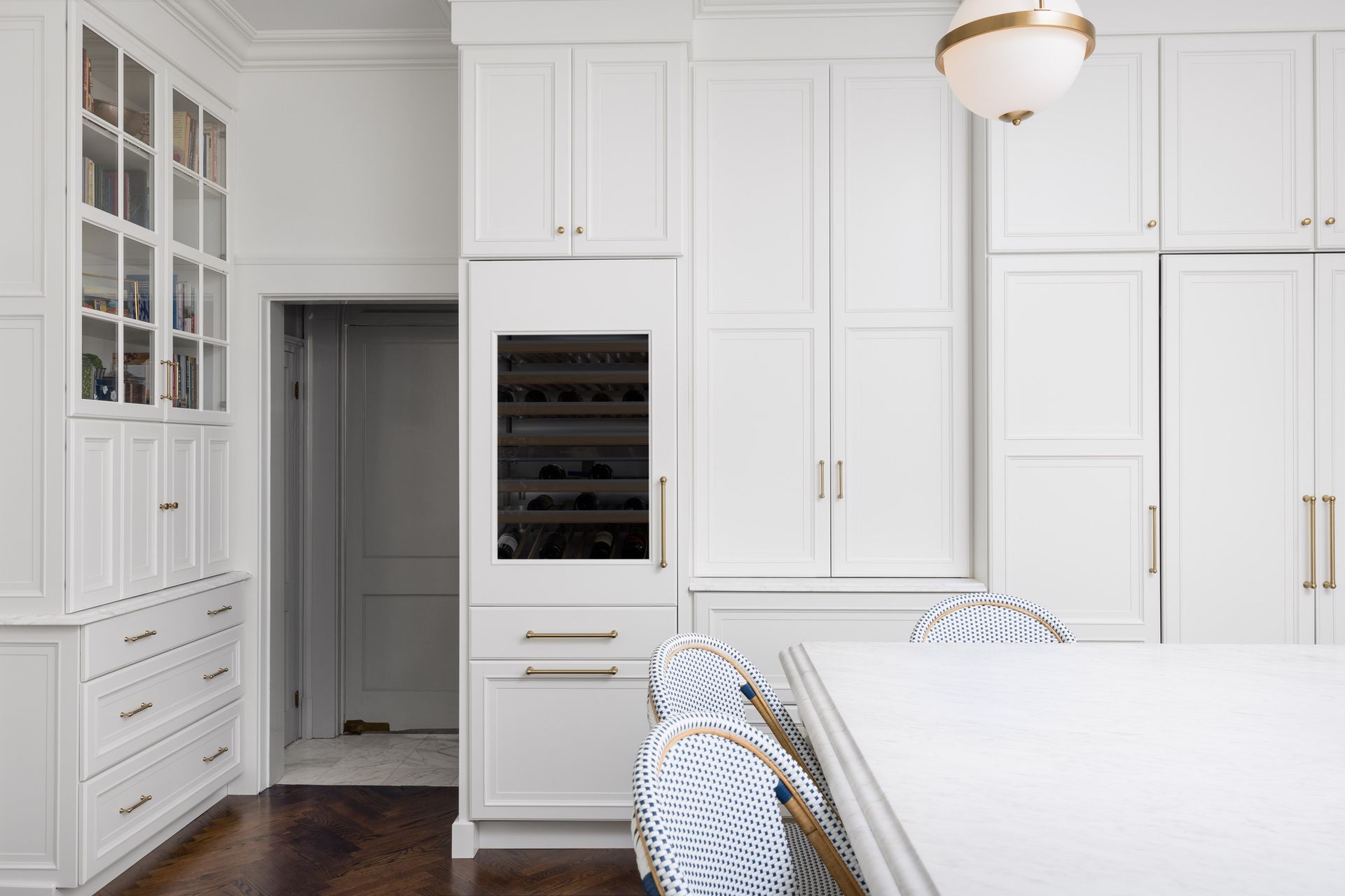White kitchen with cabinets, a wine cooler, and a white table with chairs.
