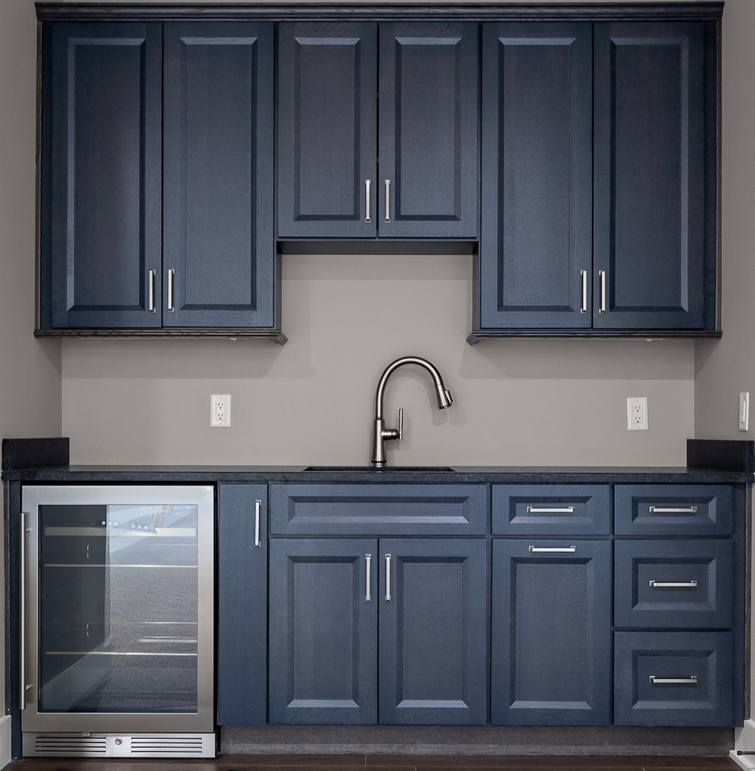 Navy blue kitchen cabinets with a sink, countertop, and wine cooler.