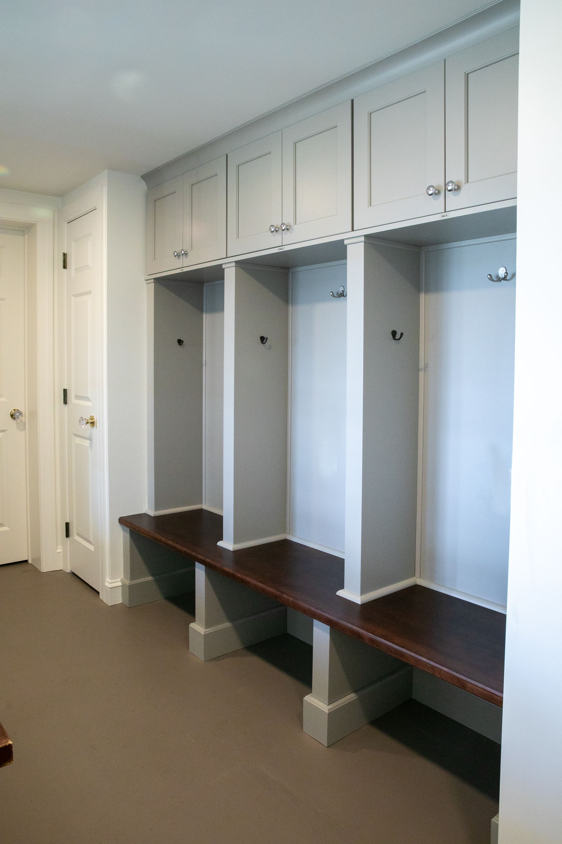 Built-in locker unit with gray cabinets, dark wood benches, and coat hooks.