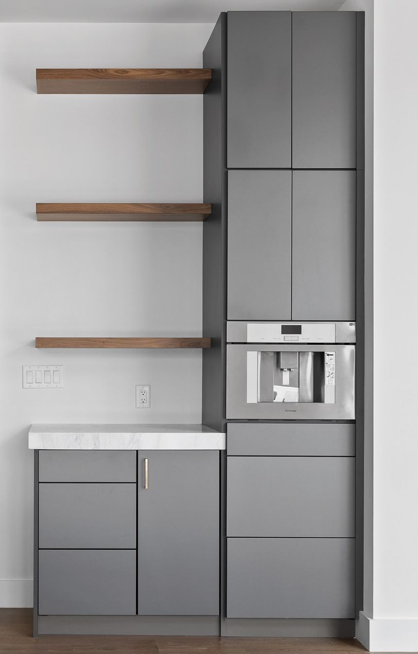 Gray built-in kitchen cabinetry with a built-in coffee maker, counter, and wooden shelves against a white wall.