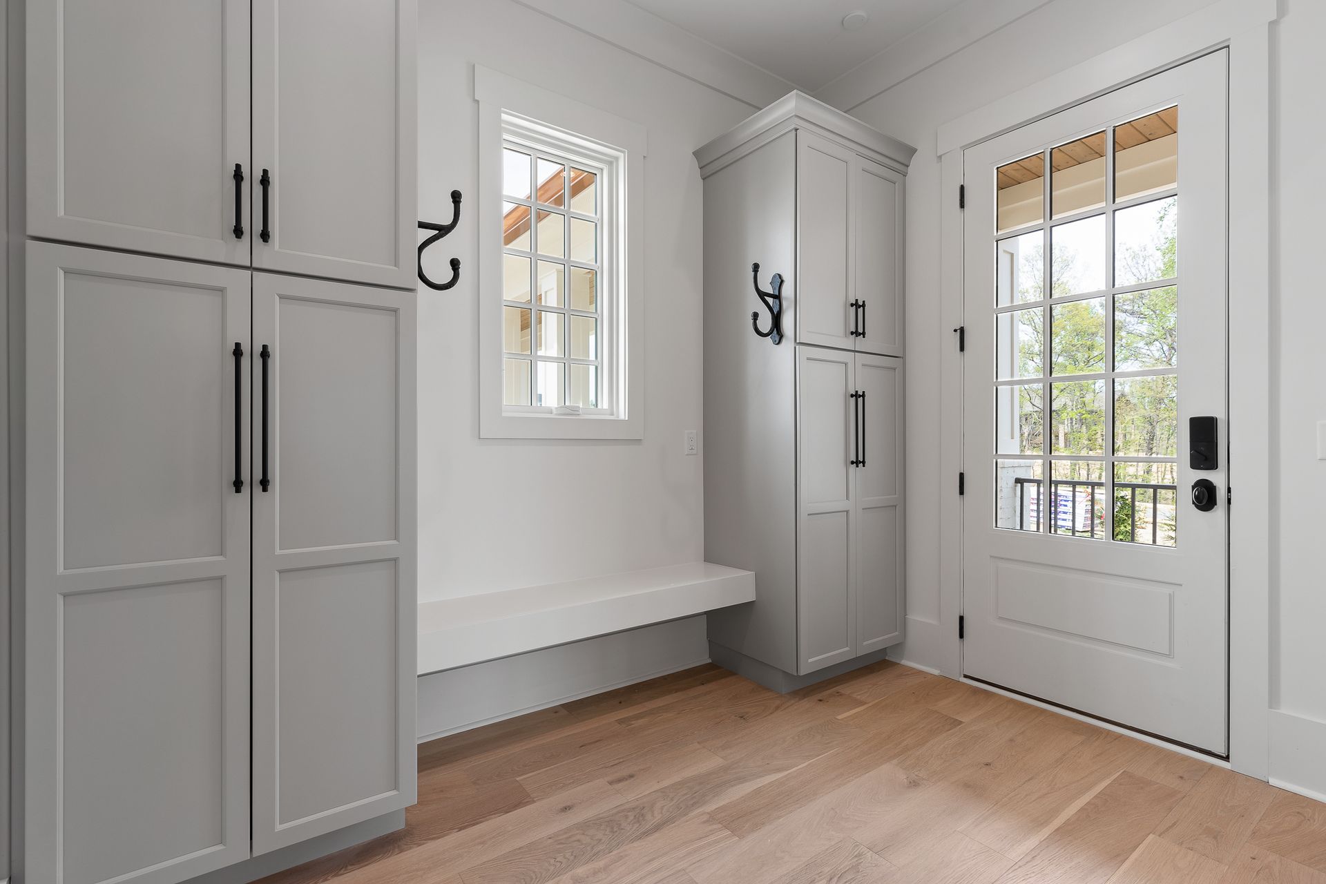 A bright entryway with gray cabinets, a bench, and a door leading to a balcony.