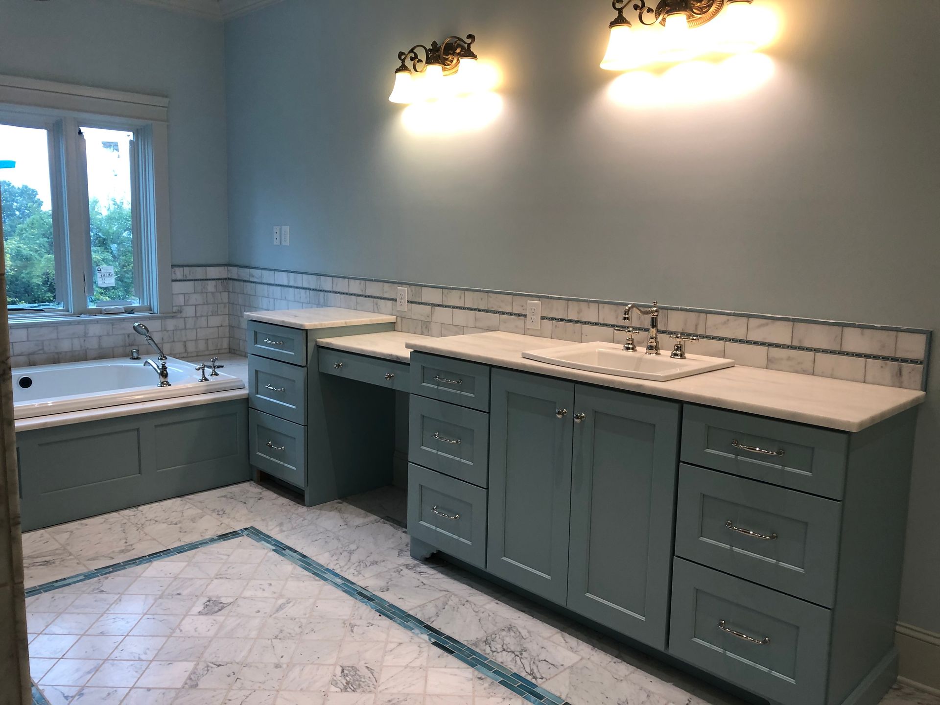 Blue bathroom with vanity, tub, and marble flooring.