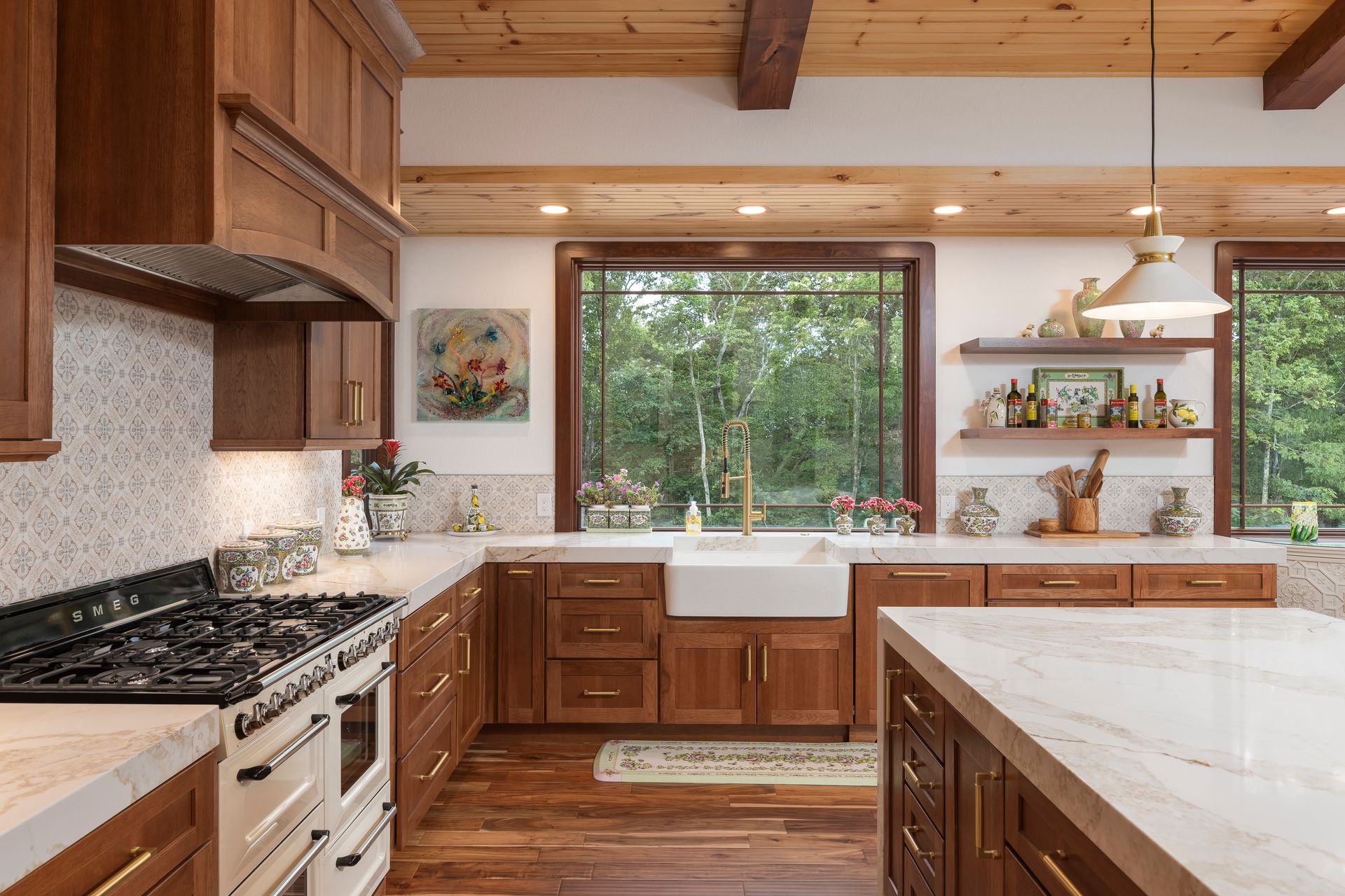Cozy kitchen with wooden cabinets, white countertops, and a large window overlooking trees.