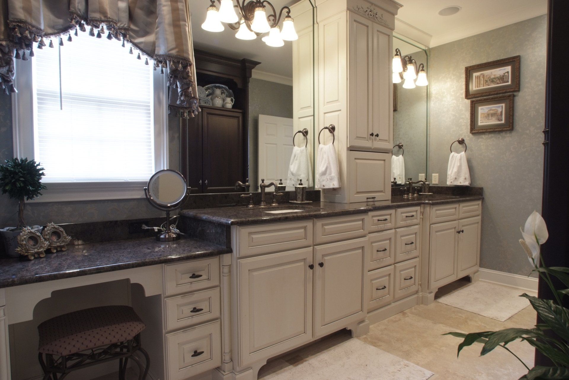 Bathroom with white cabinets, dark countertops, large mirror, and a vanity.