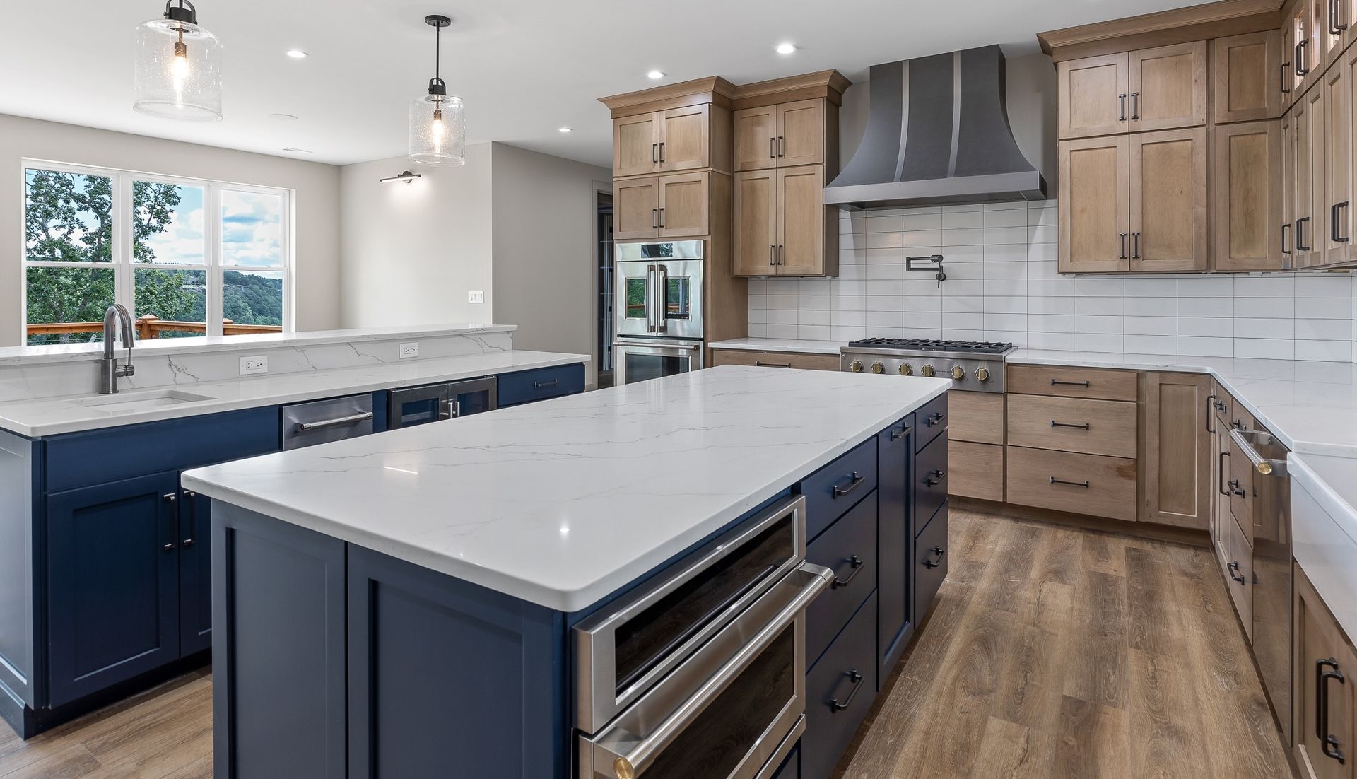 Modern kitchen with blue islands, light wood cabinets, and white countertops.