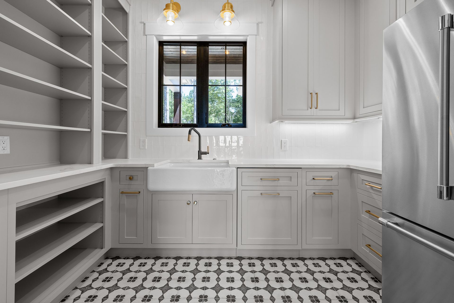 A light gray pantry with open shelving, a farmhouse sink, cabinets, and patterned floor tiles.