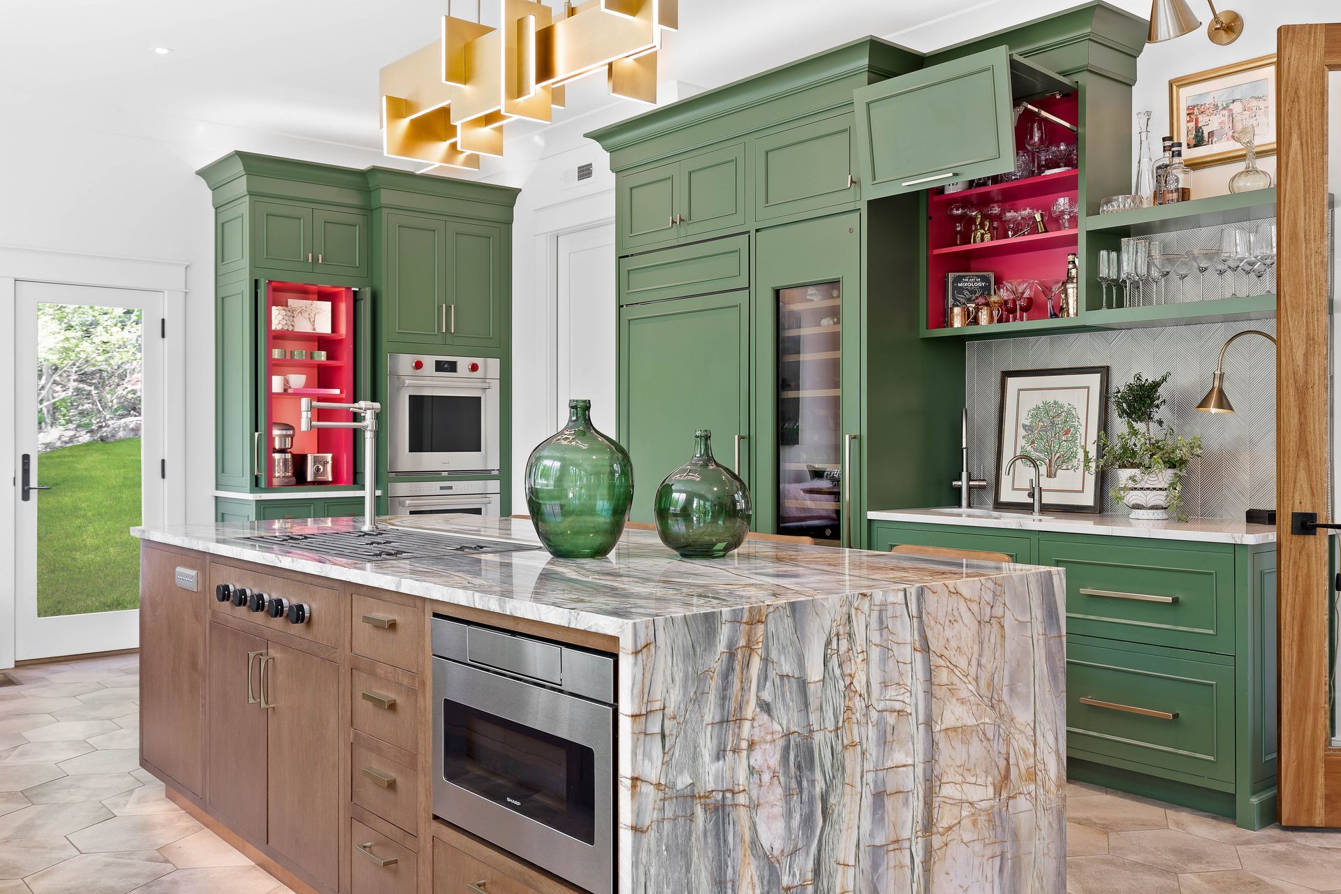 Green kitchen with a marble island and built-in appliances, with green cabinets and a red interior.