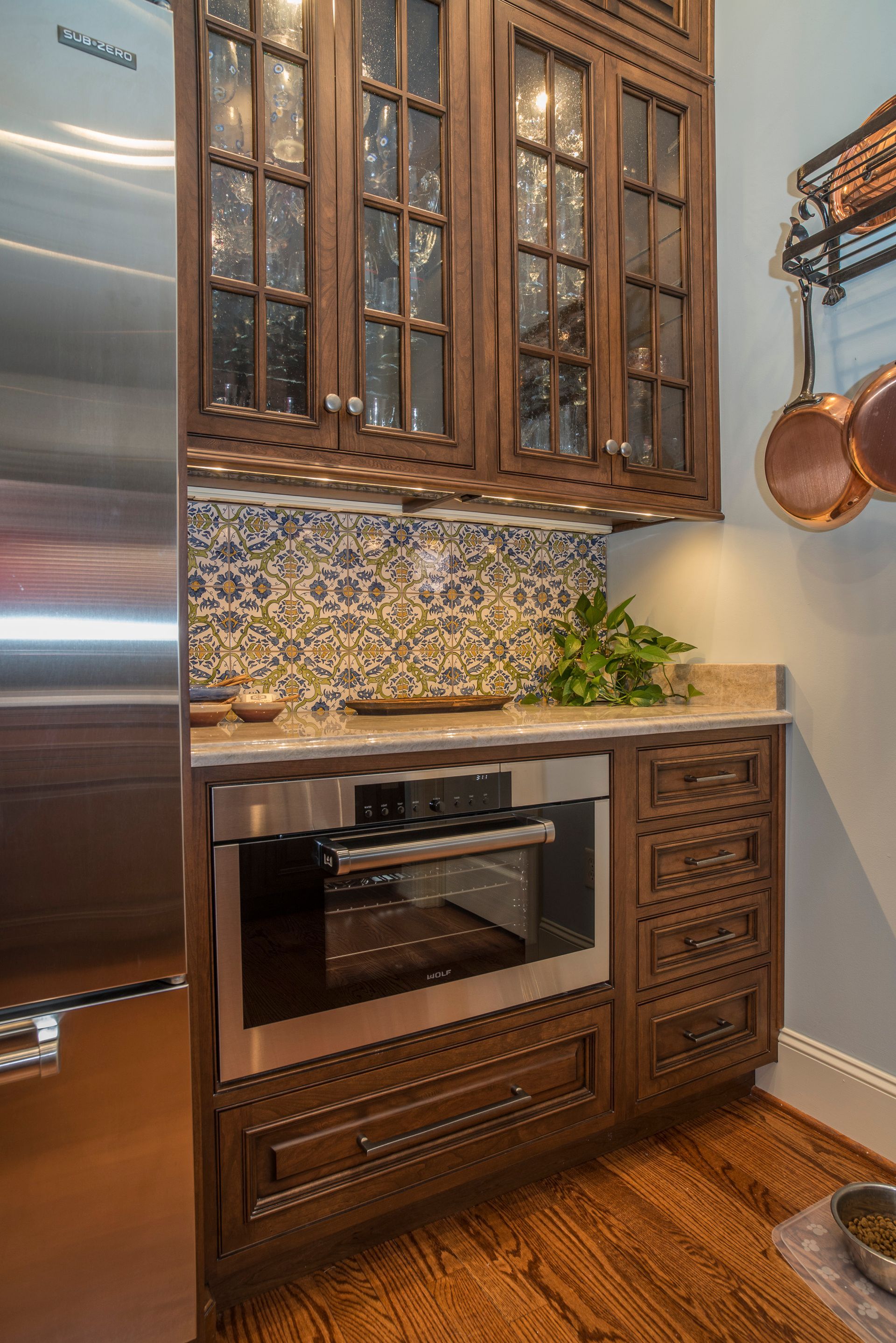 Kitchen with dark wood cabinets, stainless steel oven, and blue tile backsplash.
