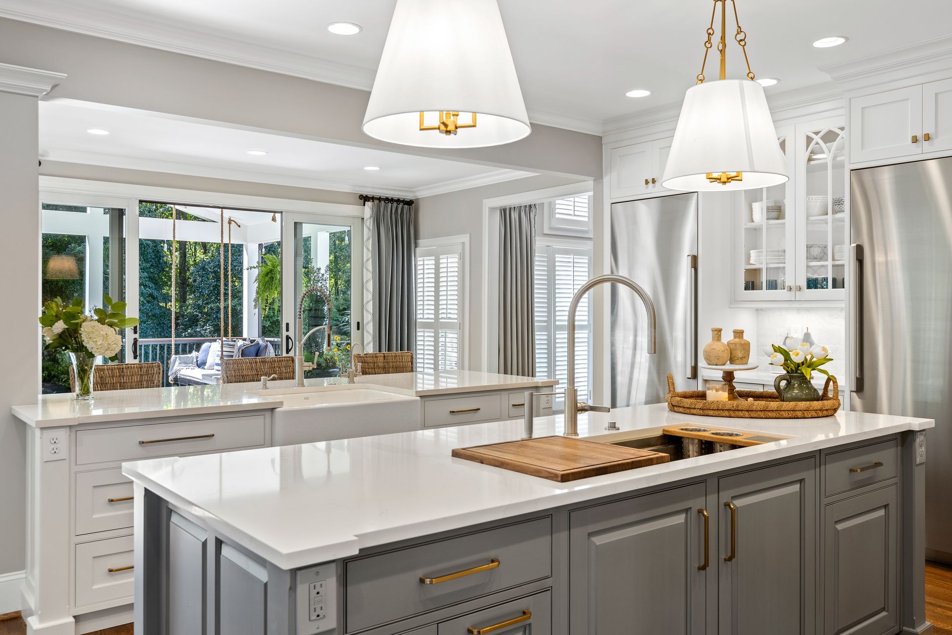 Gray and white kitchen with island, pendant lights, and view to the outdoors.