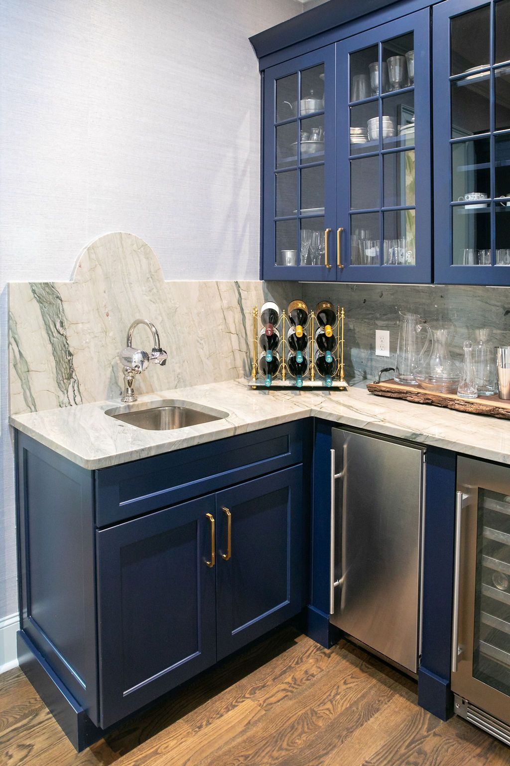 Navy blue bar area with granite countertop, stainless steel sink and appliances, and glass-front cabinets.