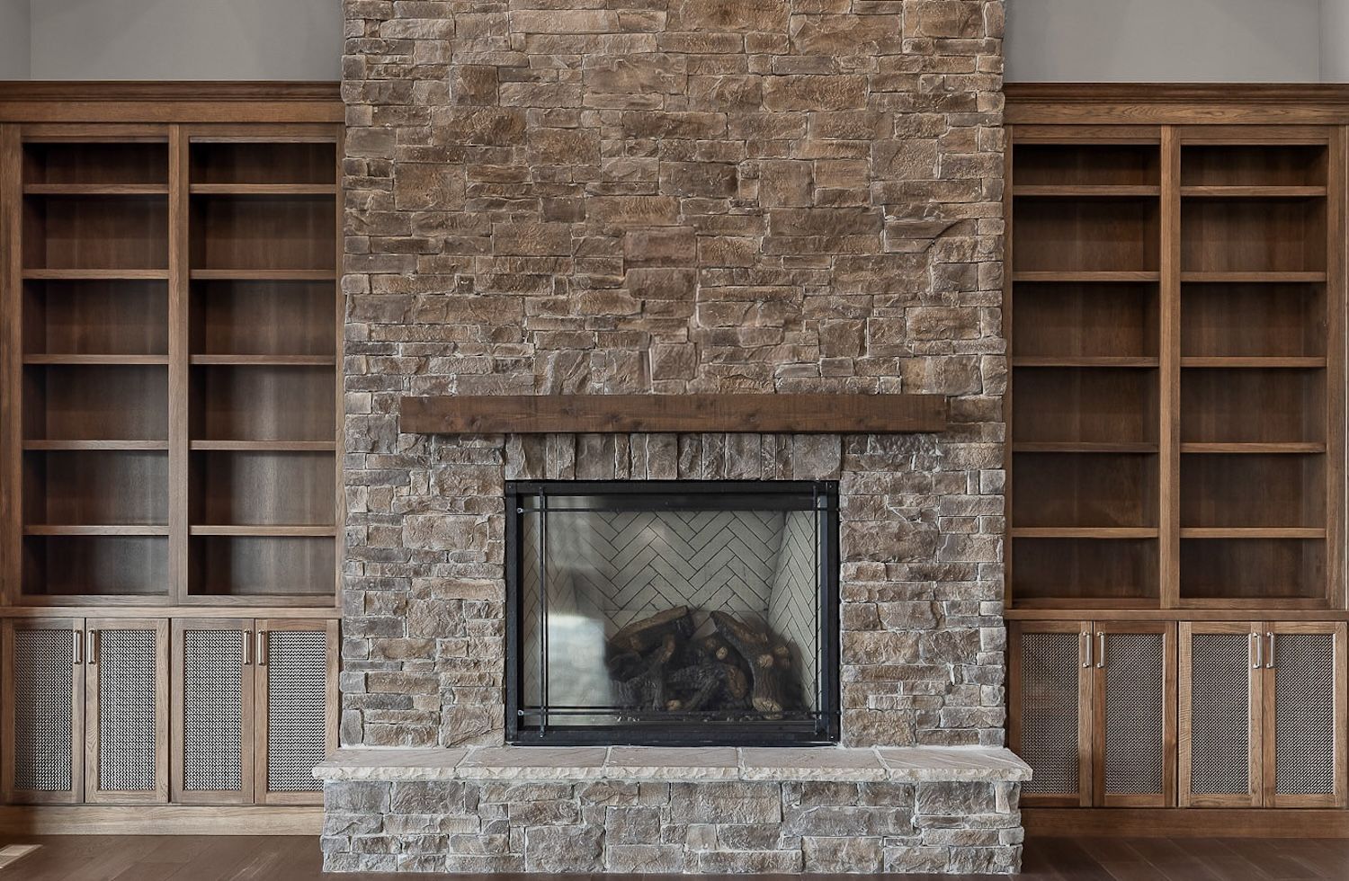 Fireplace with stone facade, wood mantel, flanked by built-in wooden bookshelves.