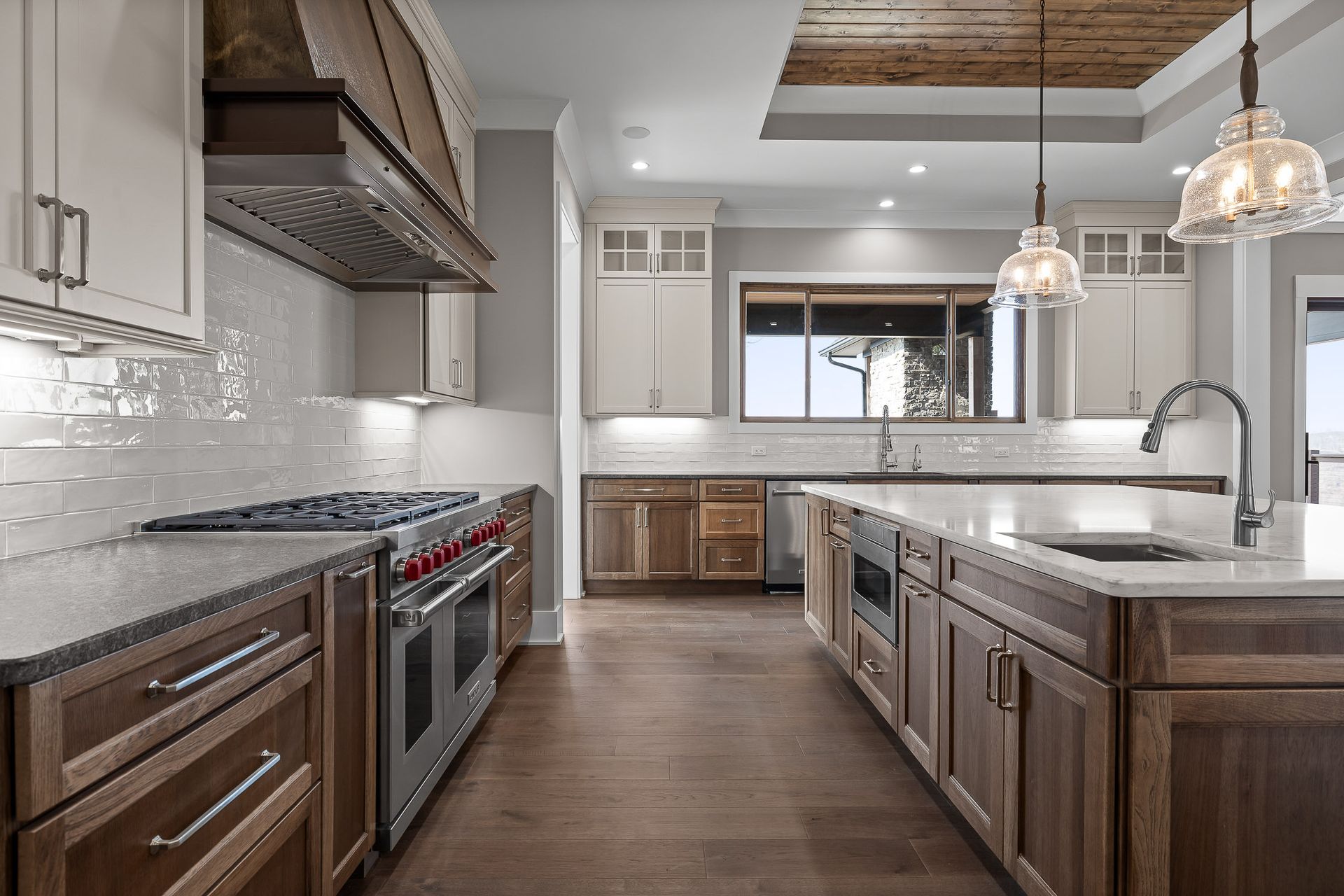 A modern kitchen with wood cabinets, white countertops, stainless steel appliances, and a large island.