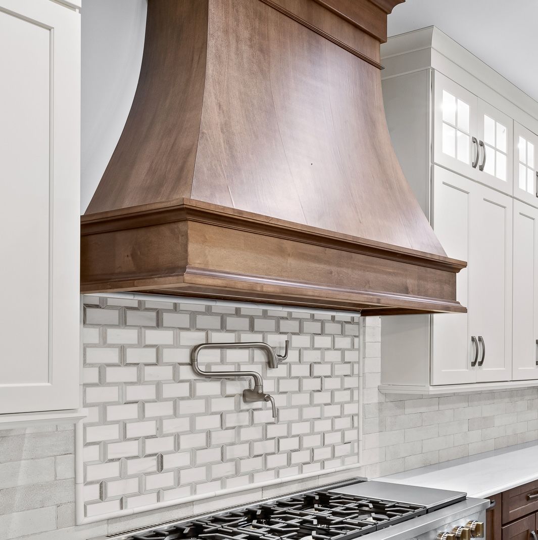 Modern kitchen with copper range hood, white subway tile backsplash, and gas cooktop