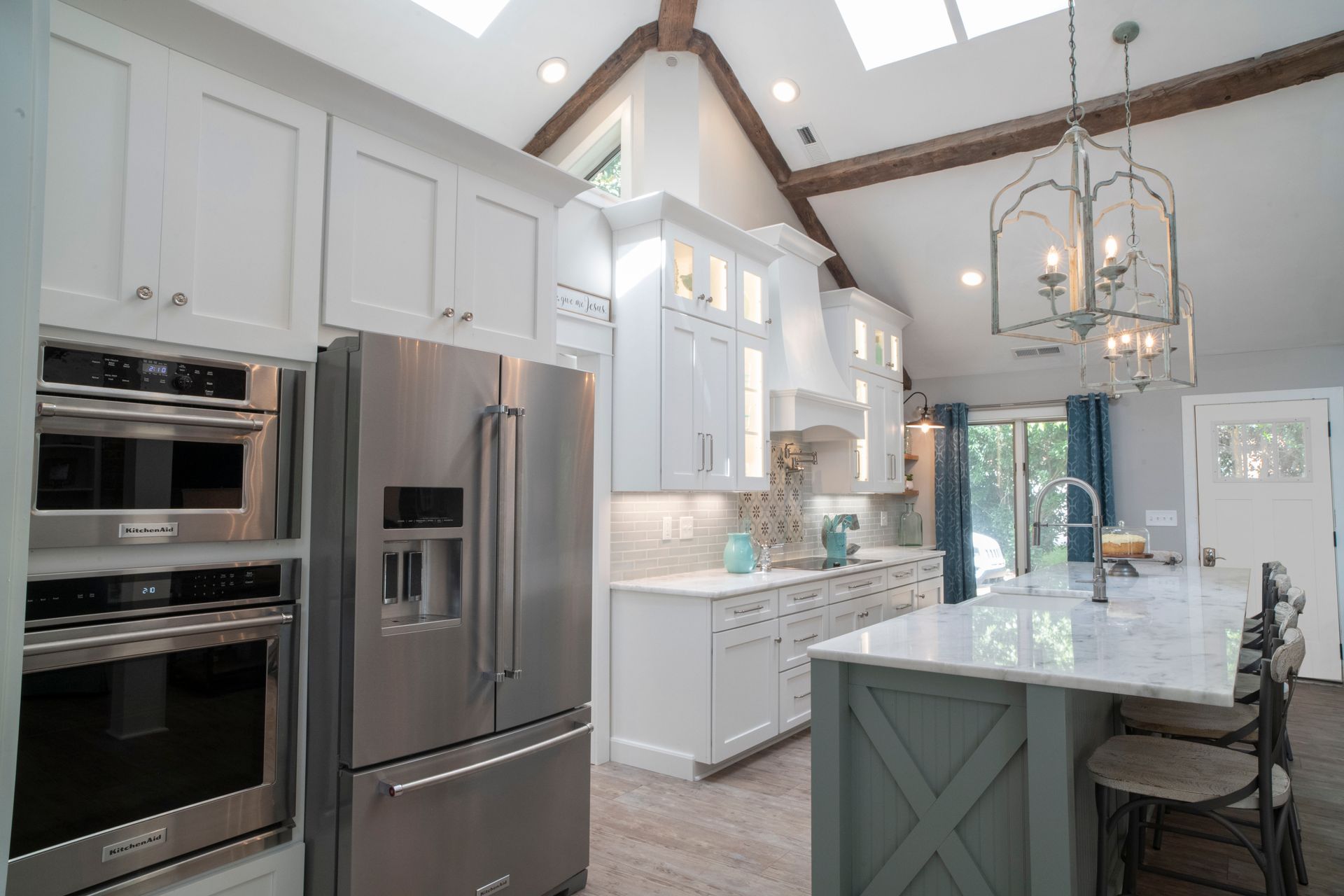 Modern kitchen with white cabinets, stainless steel appliances, and a marble-topped island.