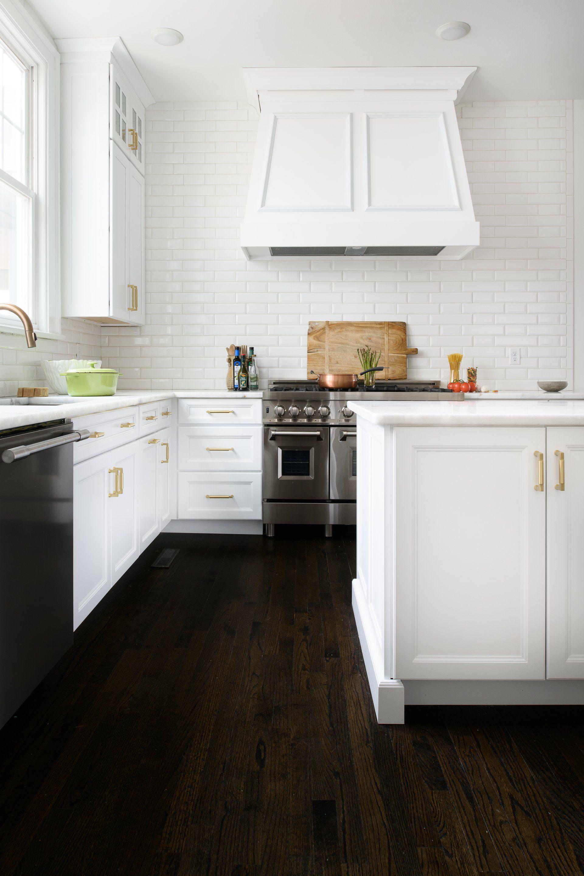 A kitchen with white cabinets , stainless steel appliances , a stove and a sink.