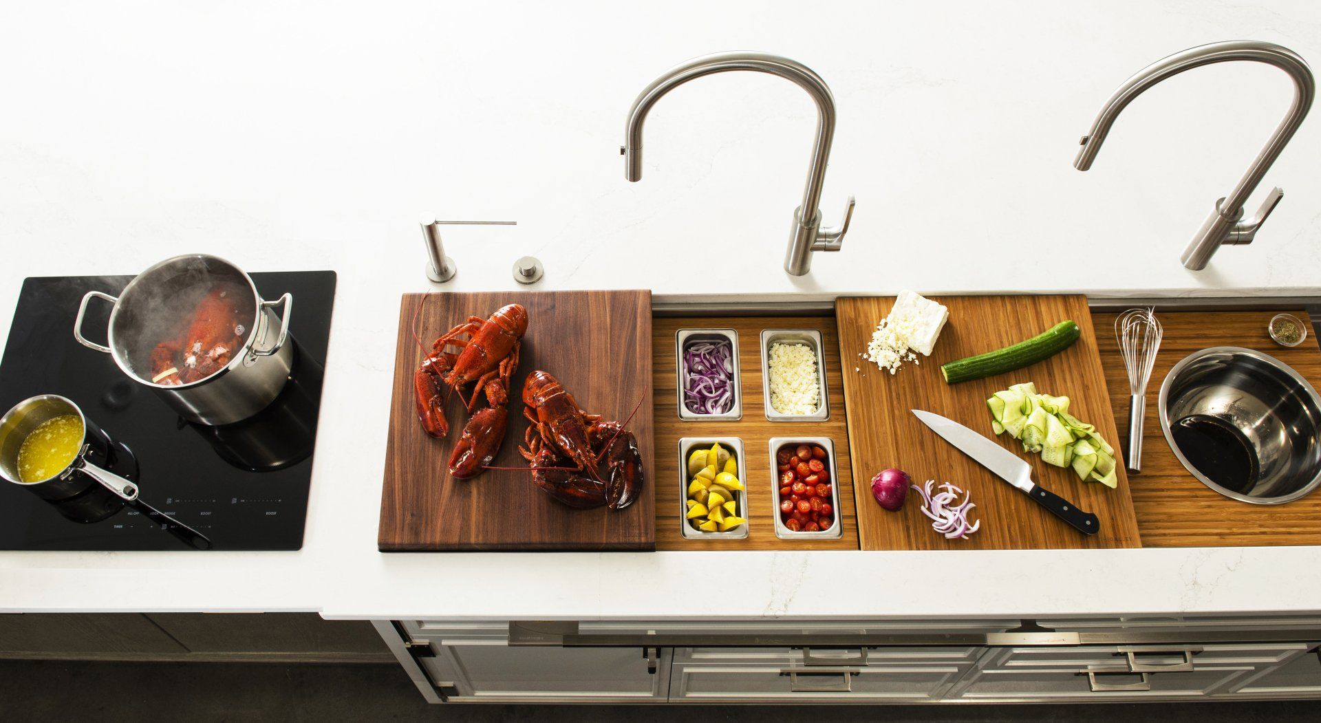 A kitchen counter with a sink , cutting boards , pots and pans.